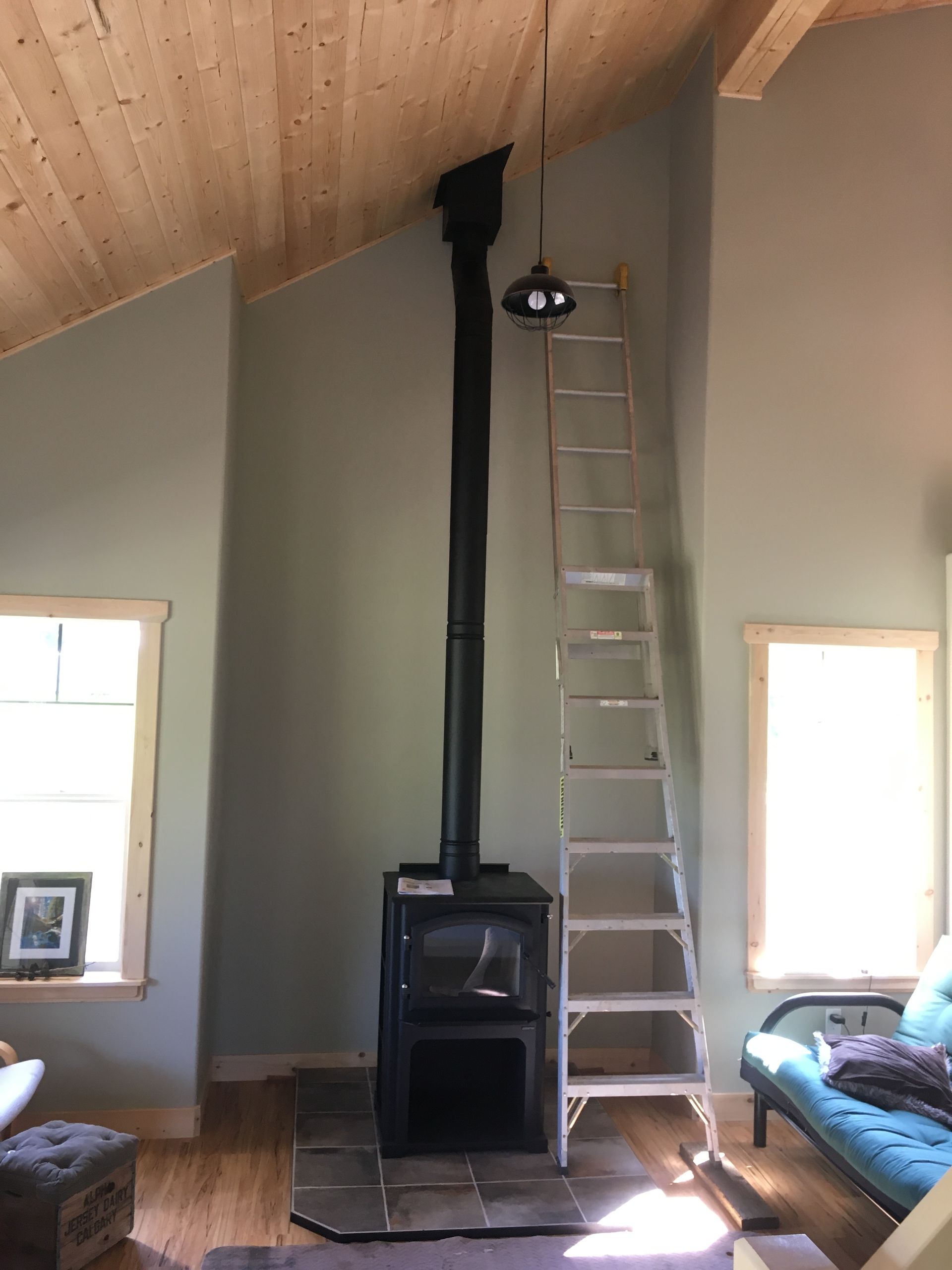 A living room with a wood stove and a ladder.