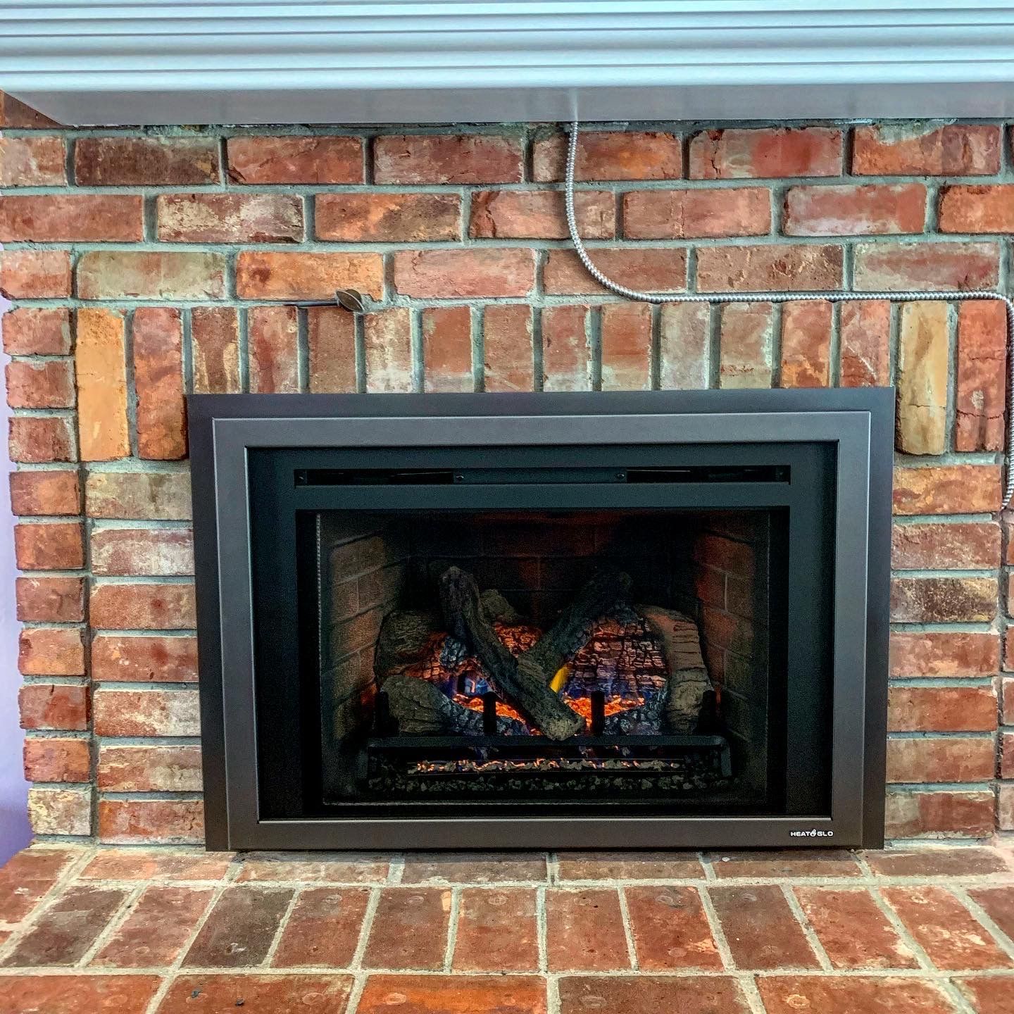 A brick fireplace with a gas fireplace insert in it.