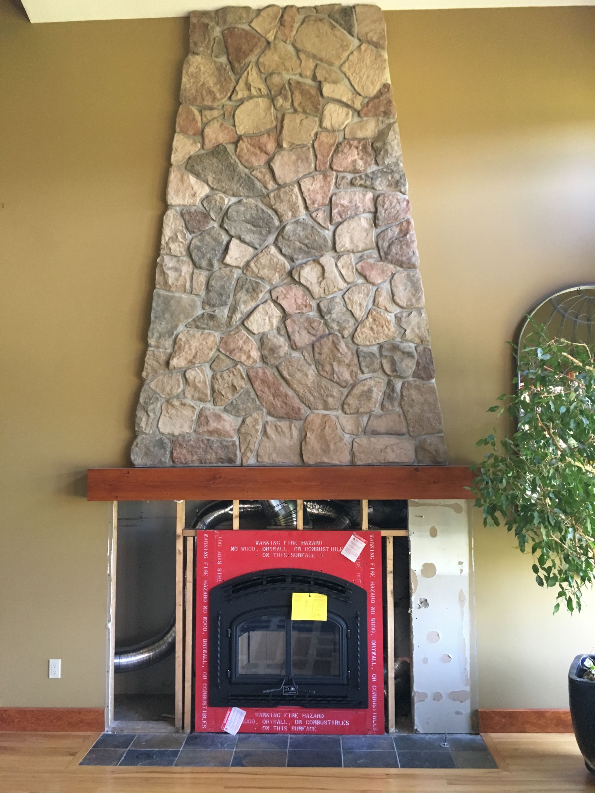 A fireplace in a living room with a large stone wall