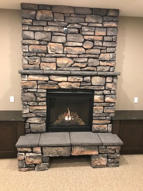 A large stone fireplace is sitting in a living room.