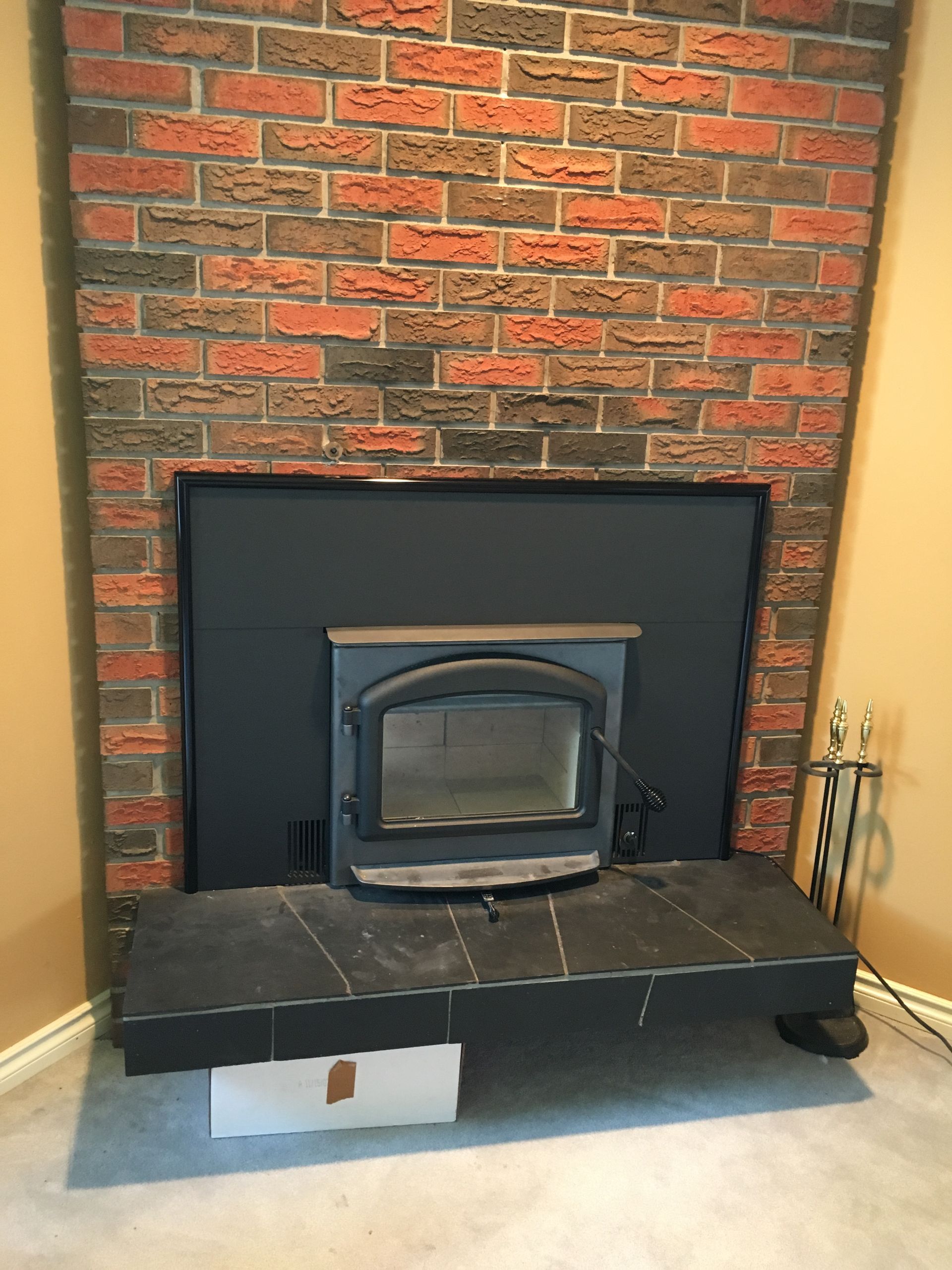 A brick fireplace with a black stove in it