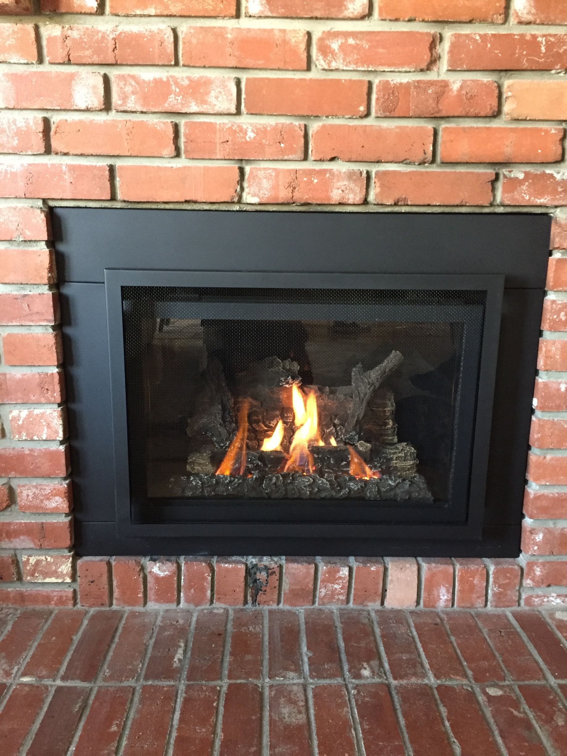 A gas fireplace is built into a brick wall.
