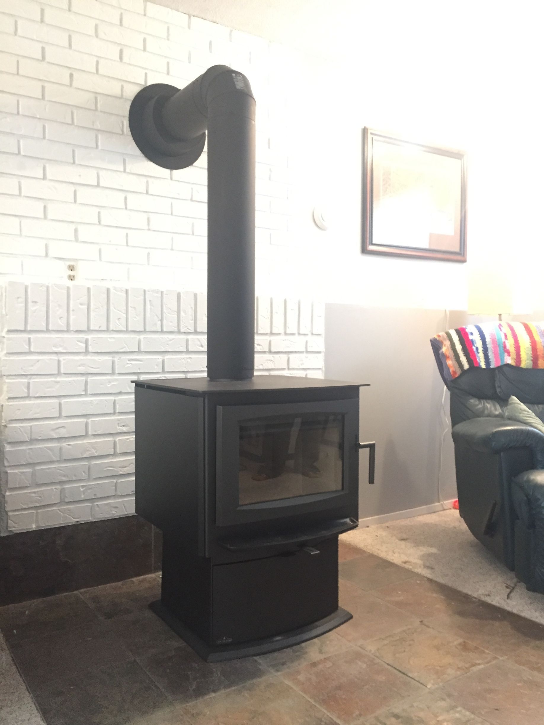 A wood stove is sitting in a living room next to a brick wall.