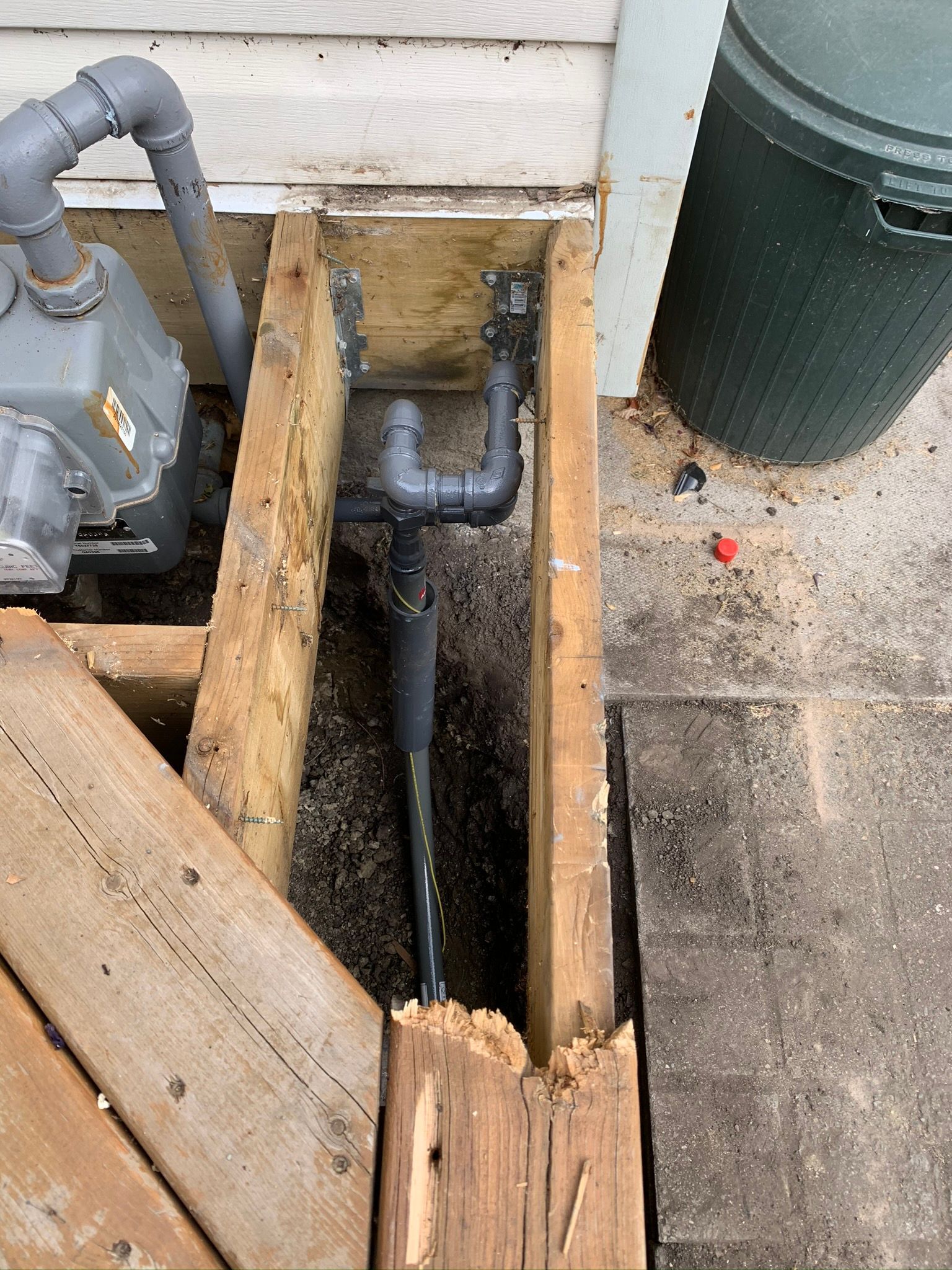 A water meter is sitting under a wooden deck.