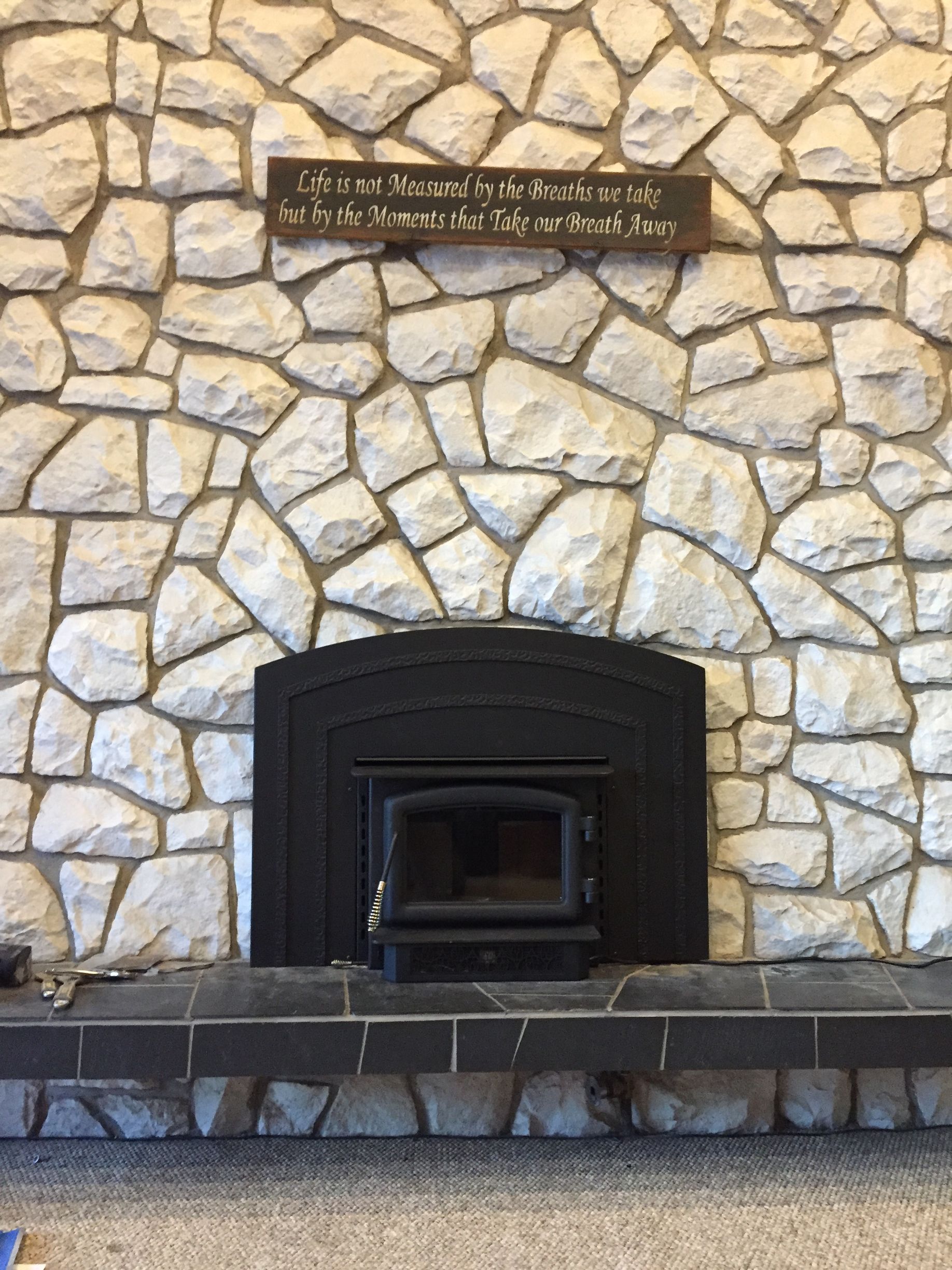 There is a fireplace in the middle of a stone wall.