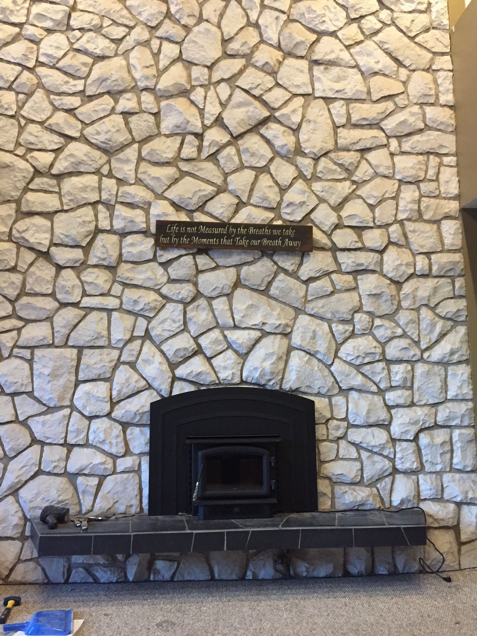 There is a fireplace in front of a stone wall.