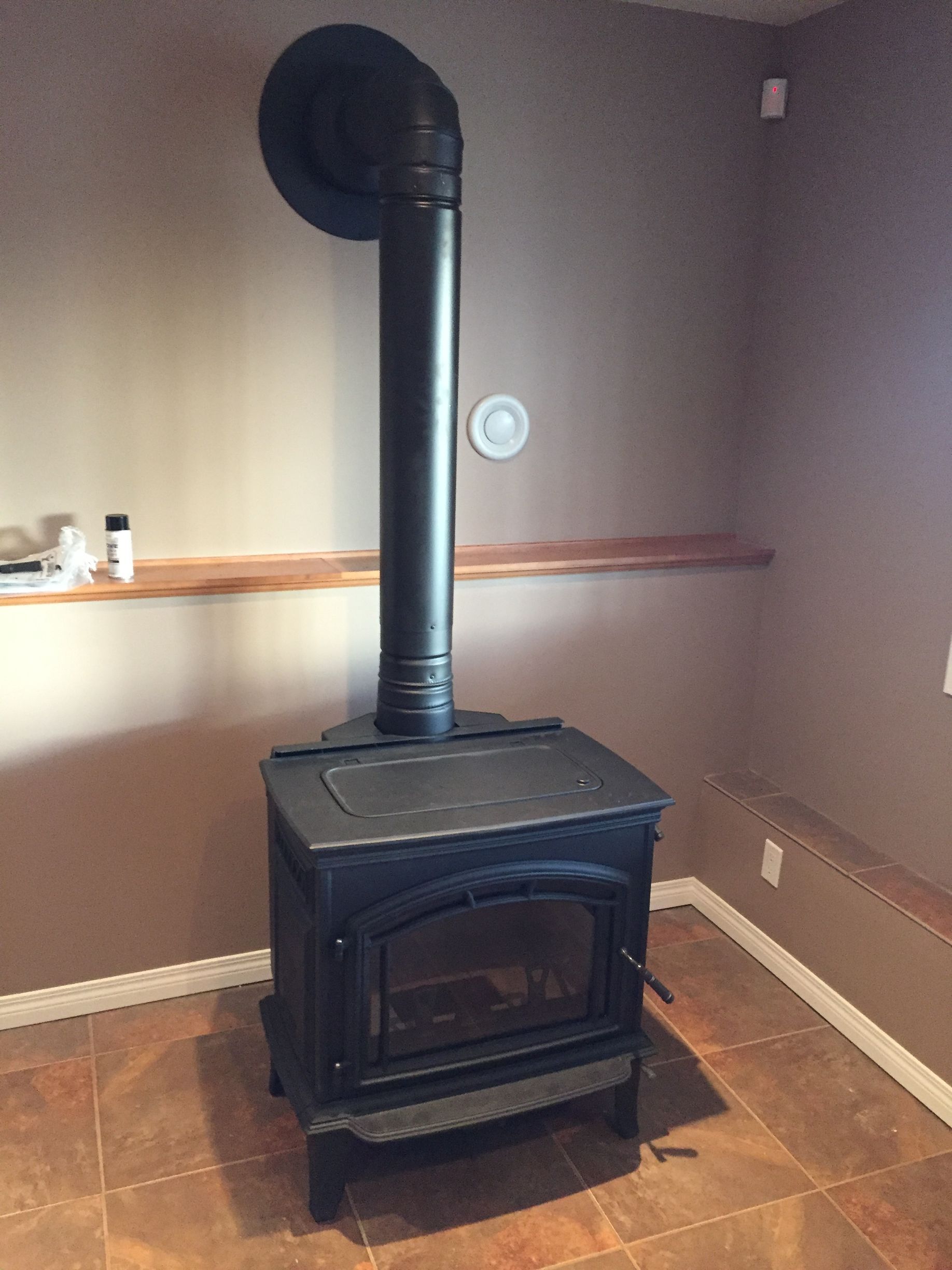 A wood stove is sitting in a room next to a wall.