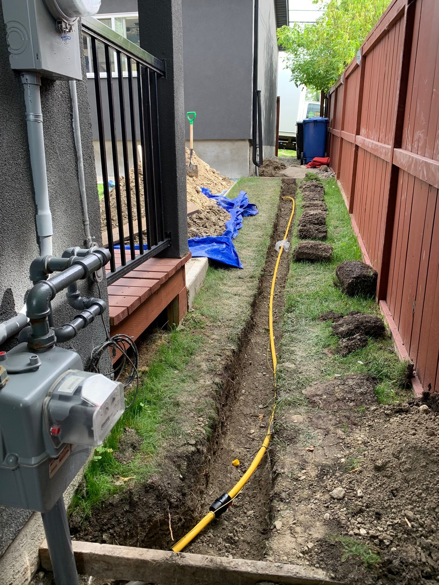 A hose is being installed in the dirt next to a fence.