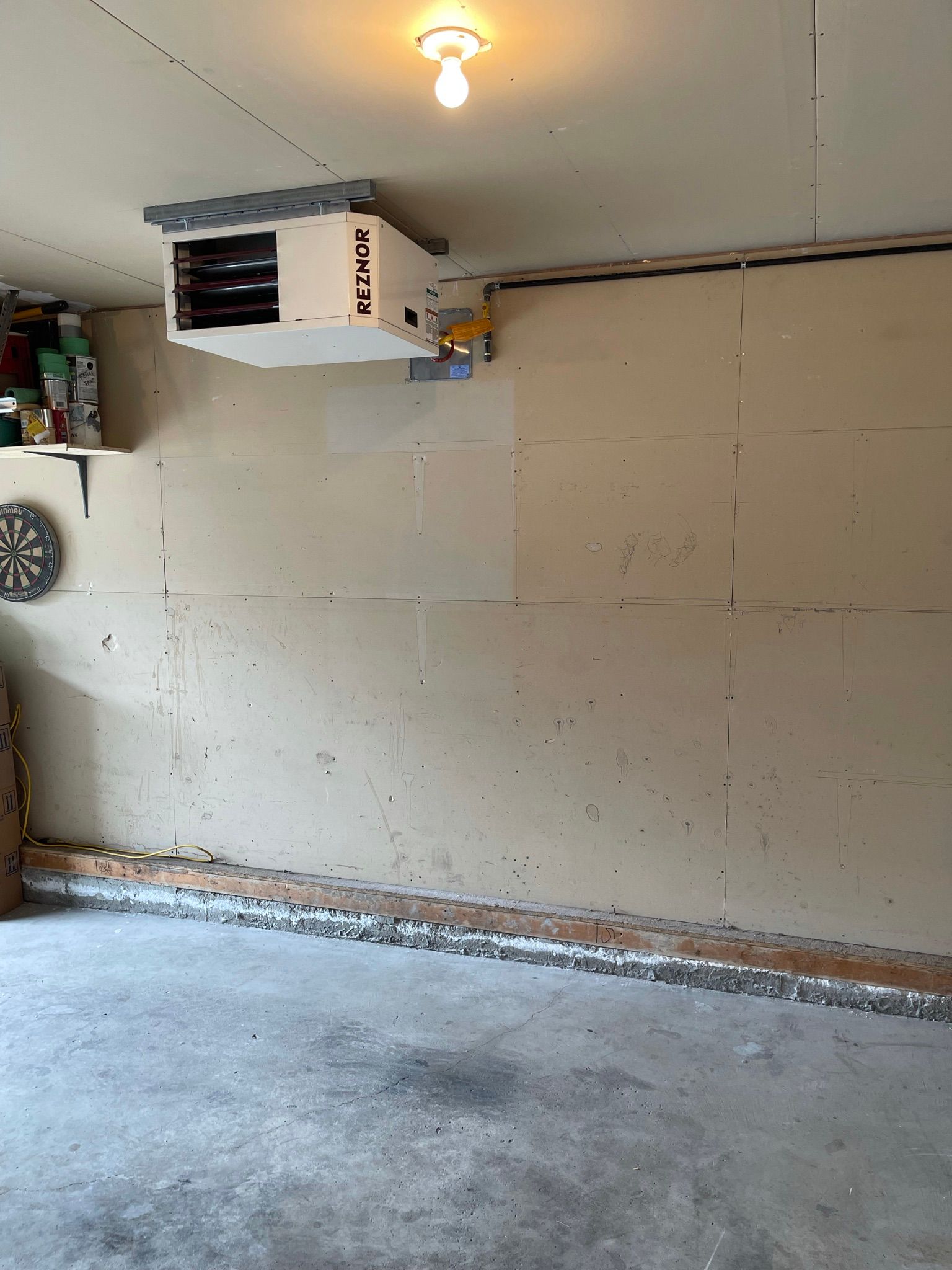 An empty garage with a heater hanging from the ceiling.