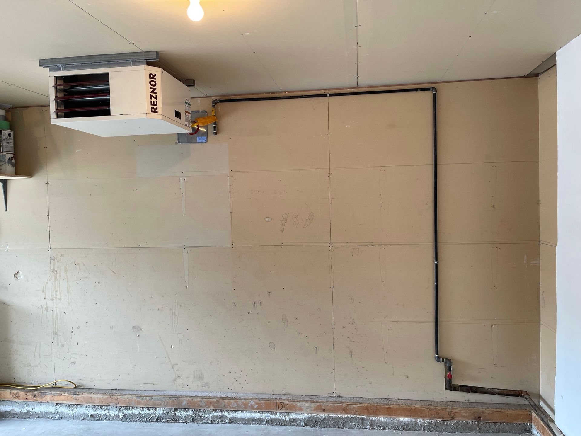 A heater is hanging from the ceiling in a garage