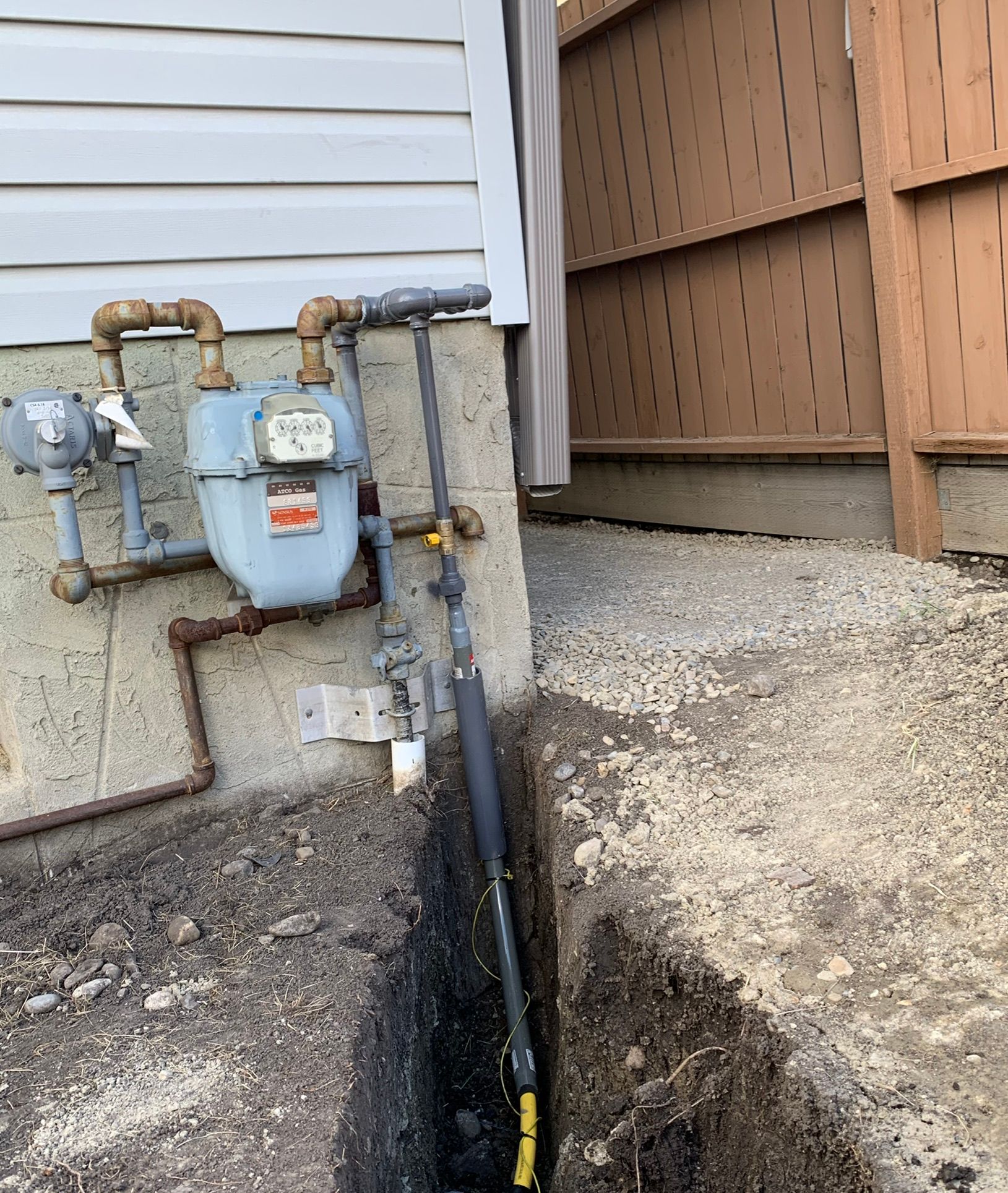 A gas meter is attached to the side of a house.