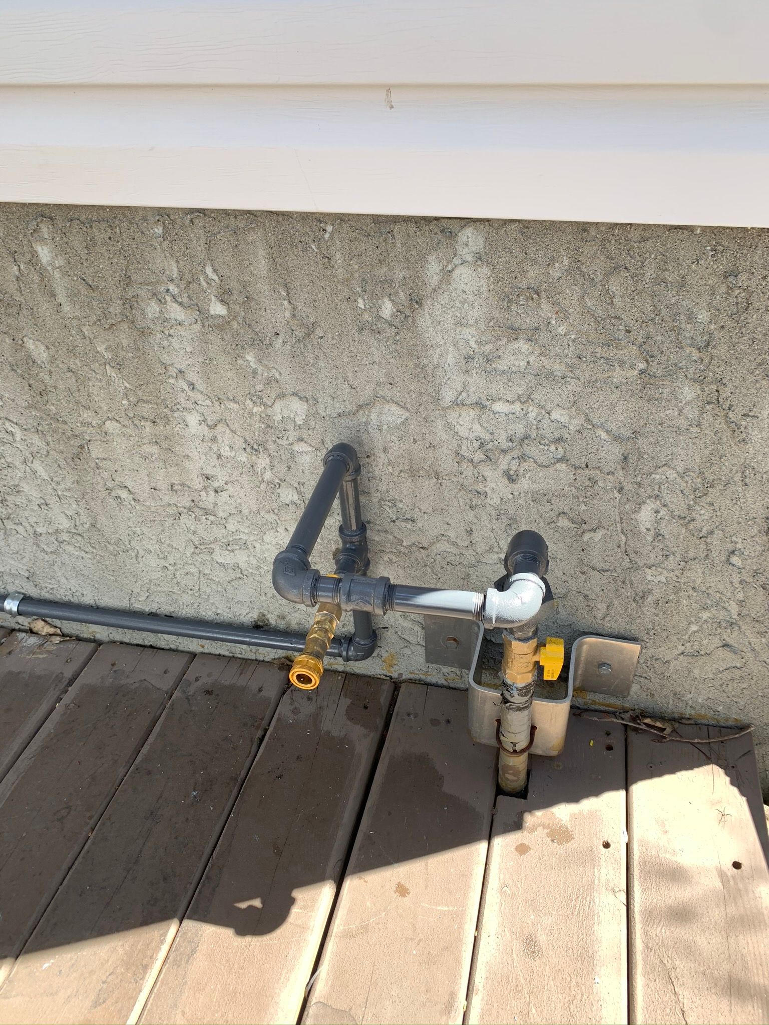 A hose is attached to a wall on a wooden deck.
