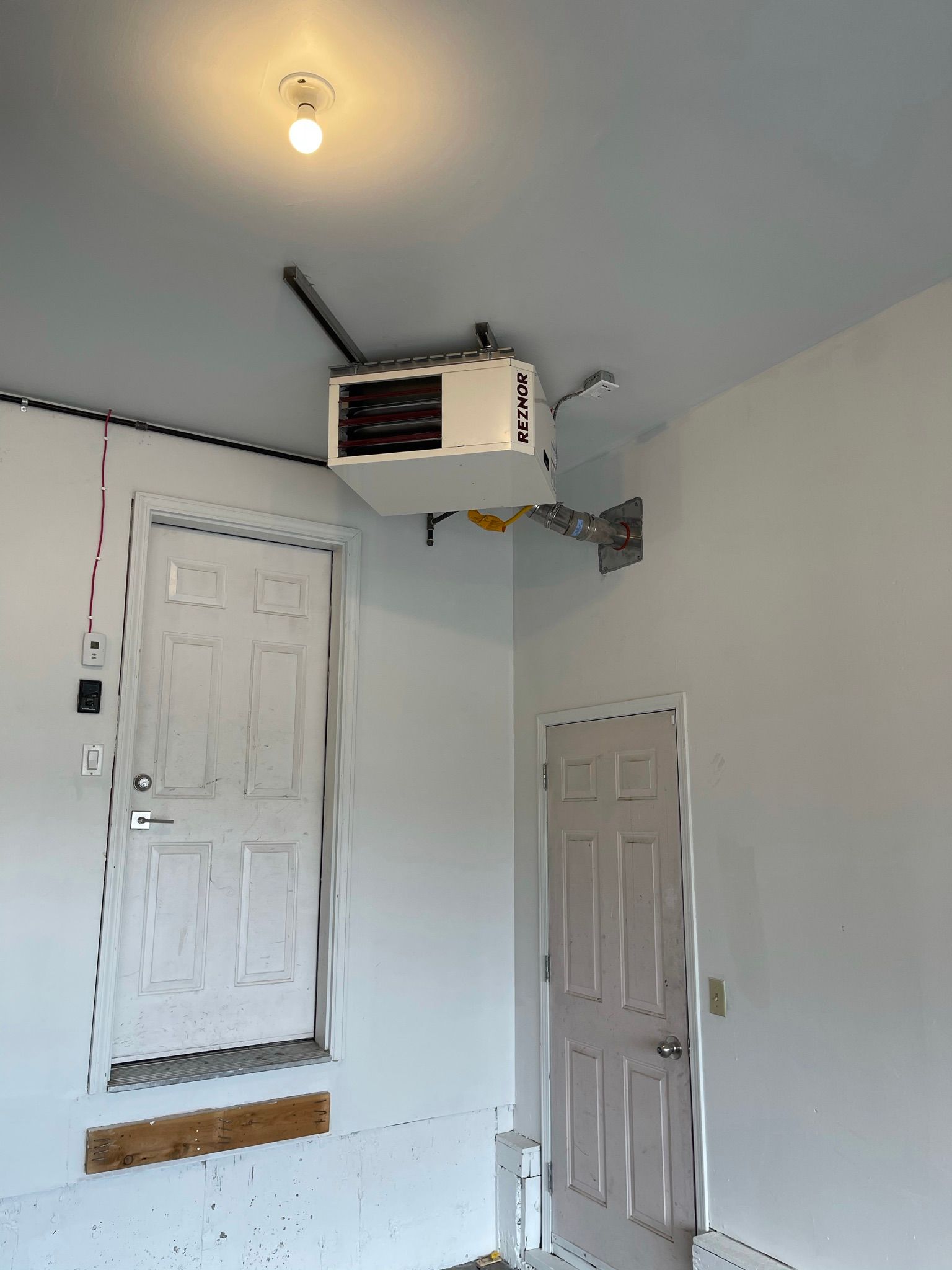 A garage door opener is hanging from the ceiling above a door.