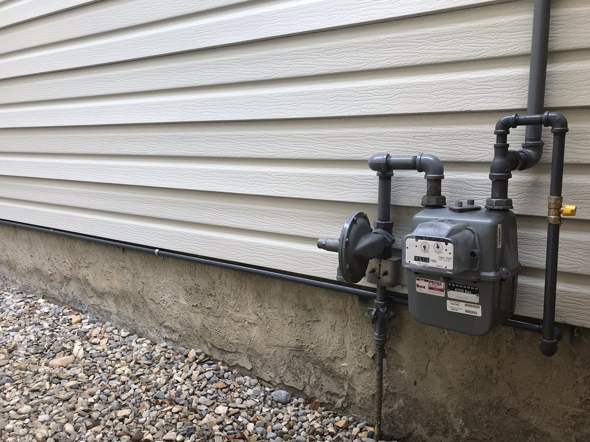 A gas meter is attached to the side of a house.
