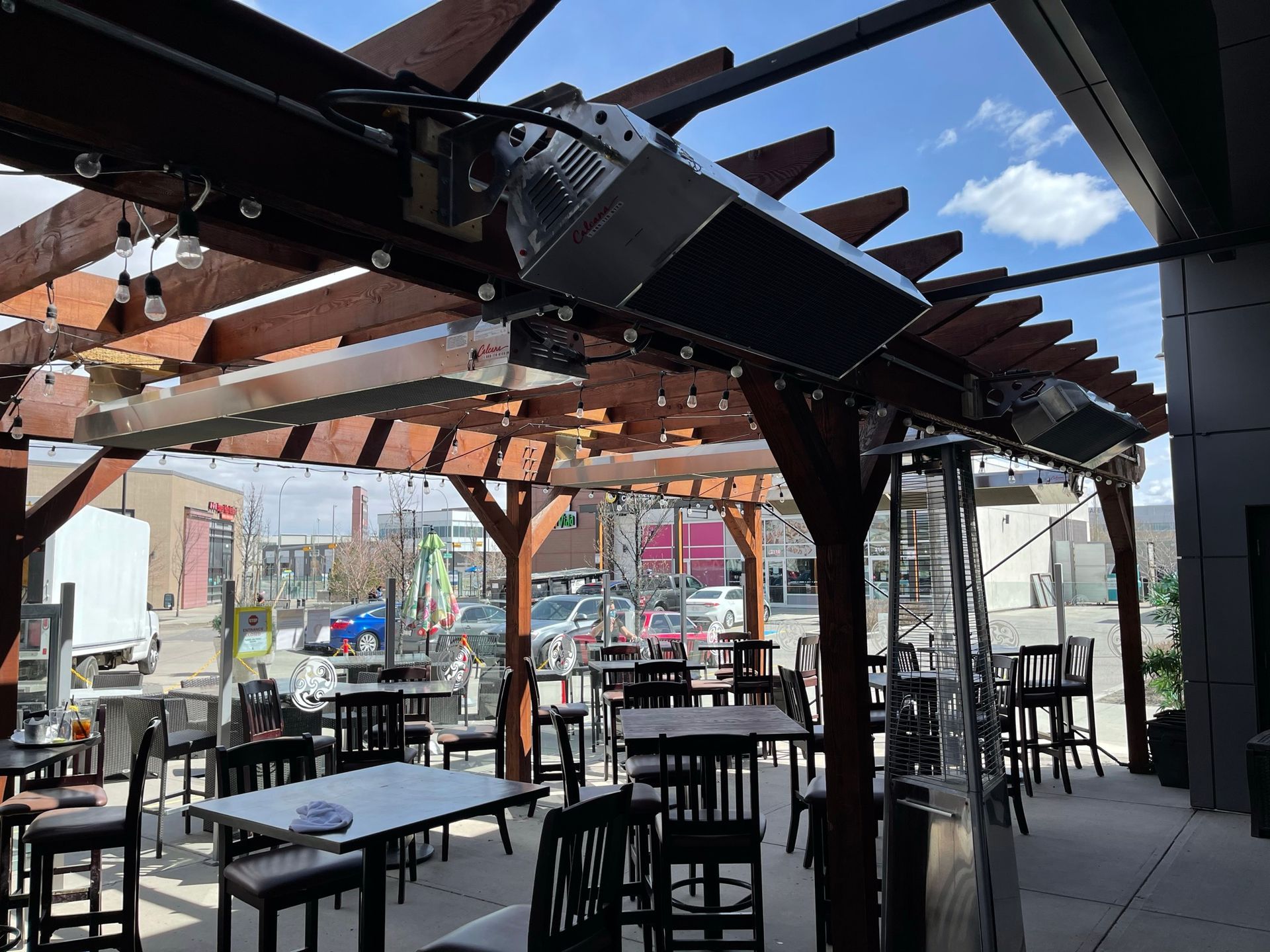 A restaurant with tables and chairs under a pergola.