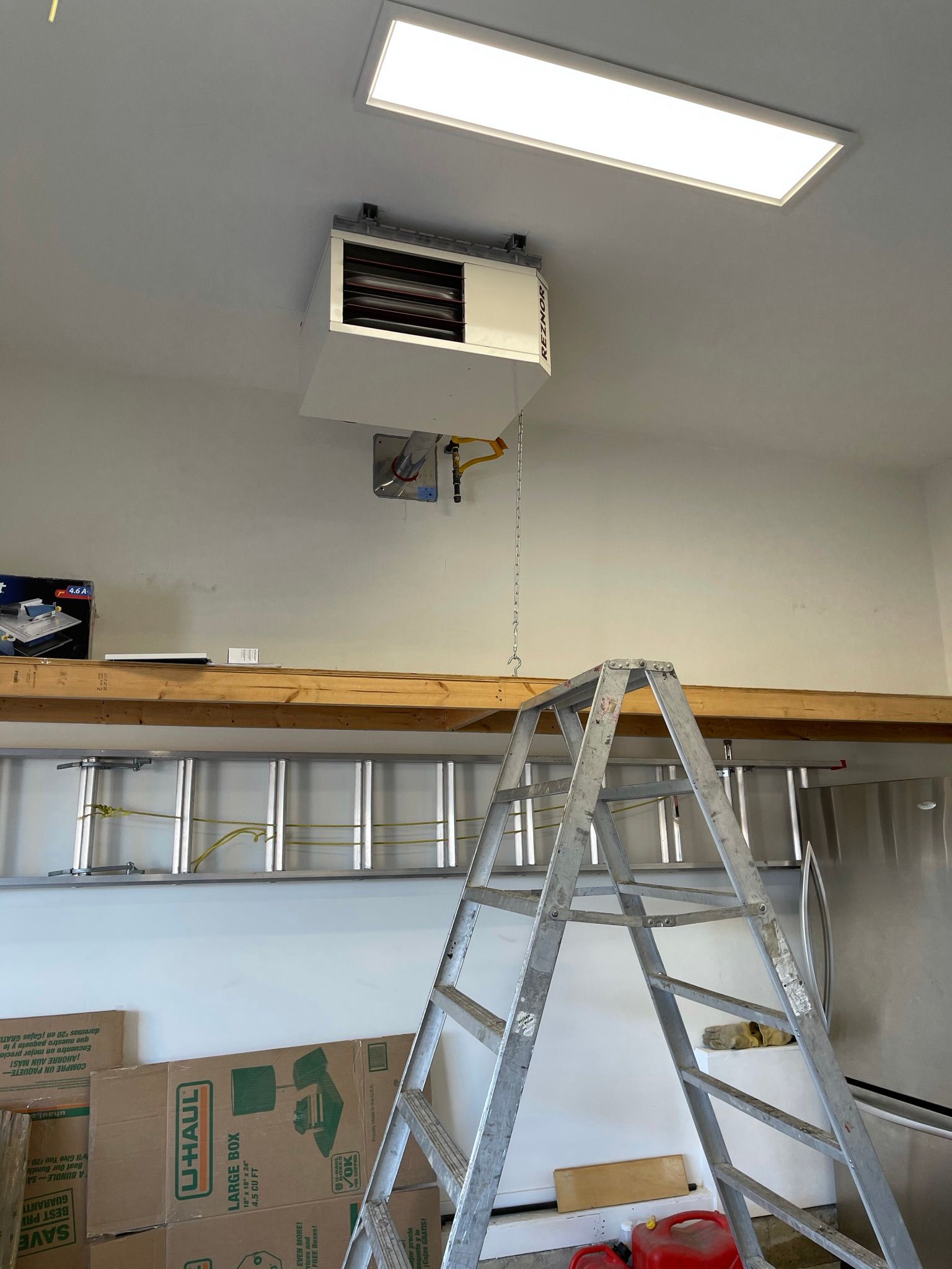 A ladder is sitting on top of a wooden shelf in a garage.