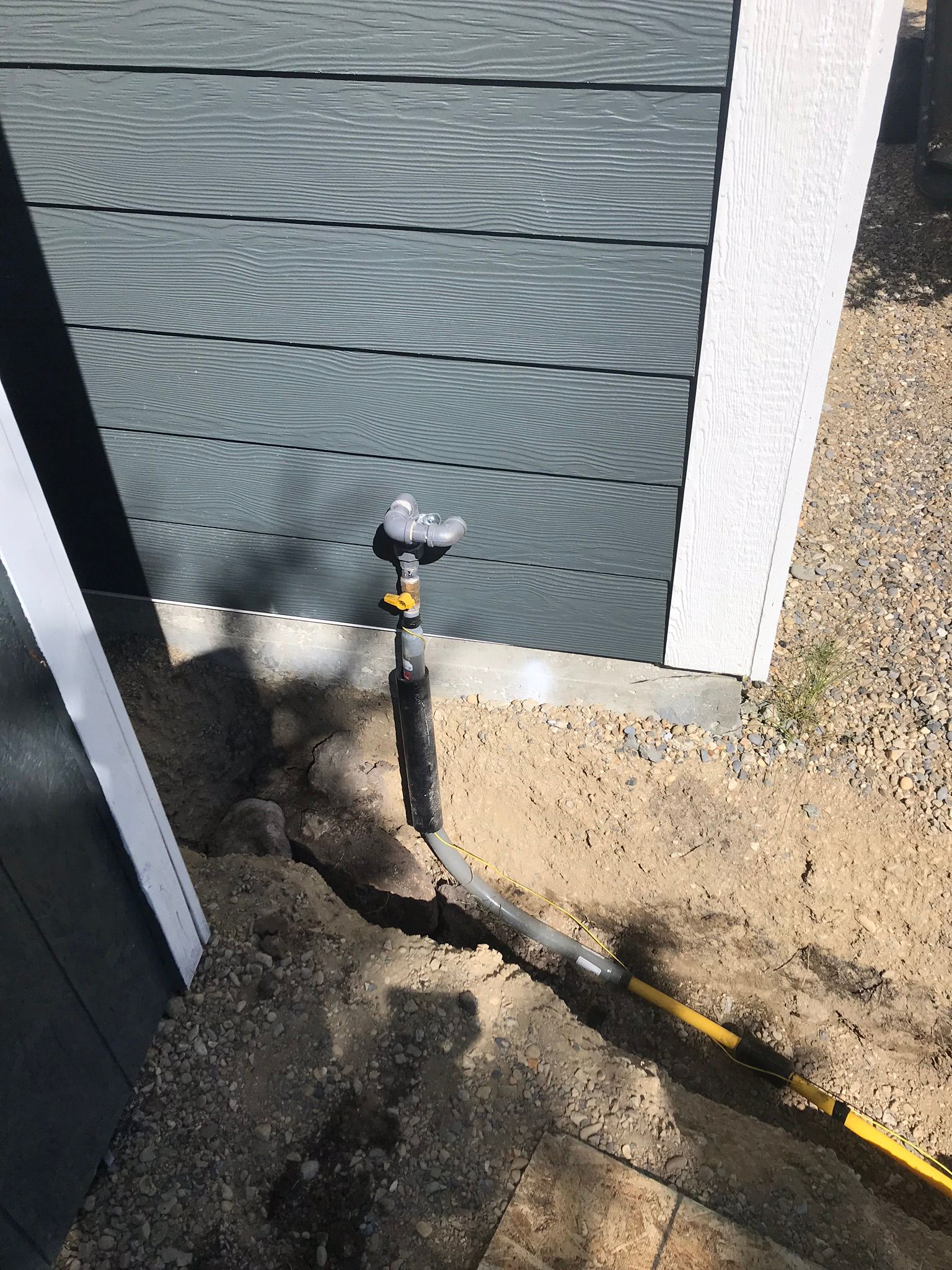 A hose is connected to a sprinkler on the side of a building.
