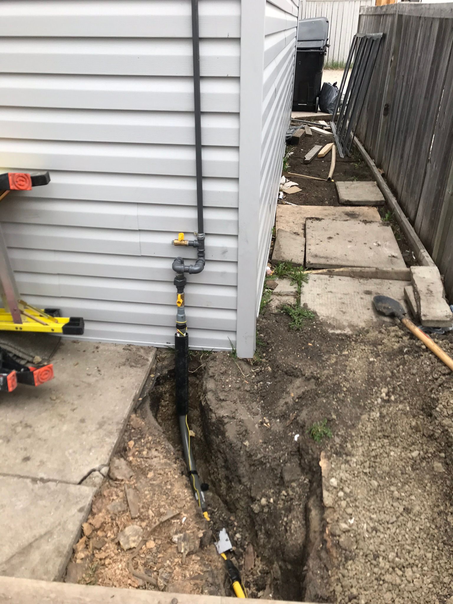 A pipe is being installed on the side of a house.