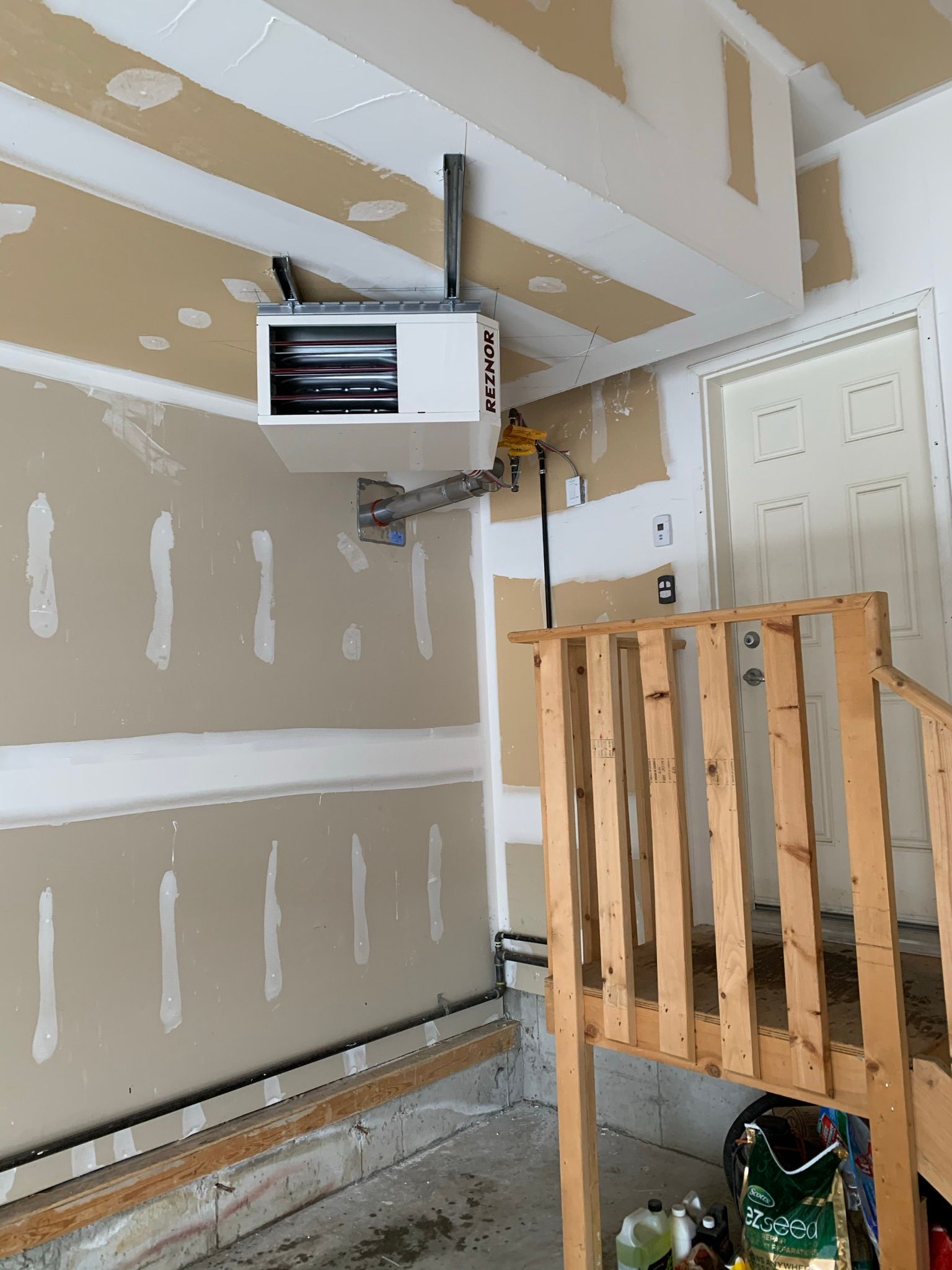 A garage with a heater hanging from the ceiling and a wooden railing.