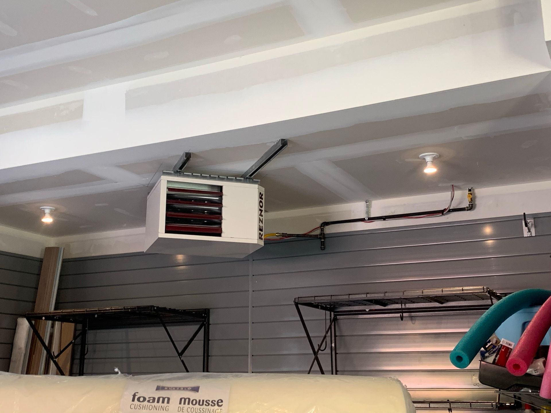 A heater is hanging from the ceiling of a garage.