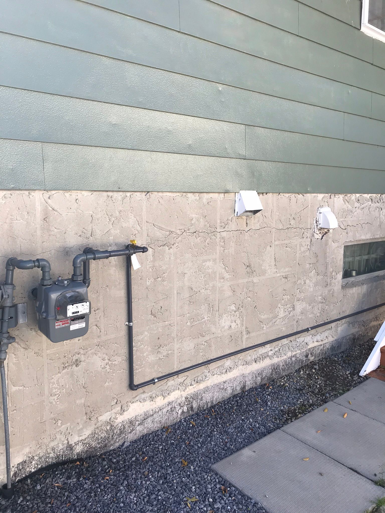 A gas meter is attached to the side of a house.