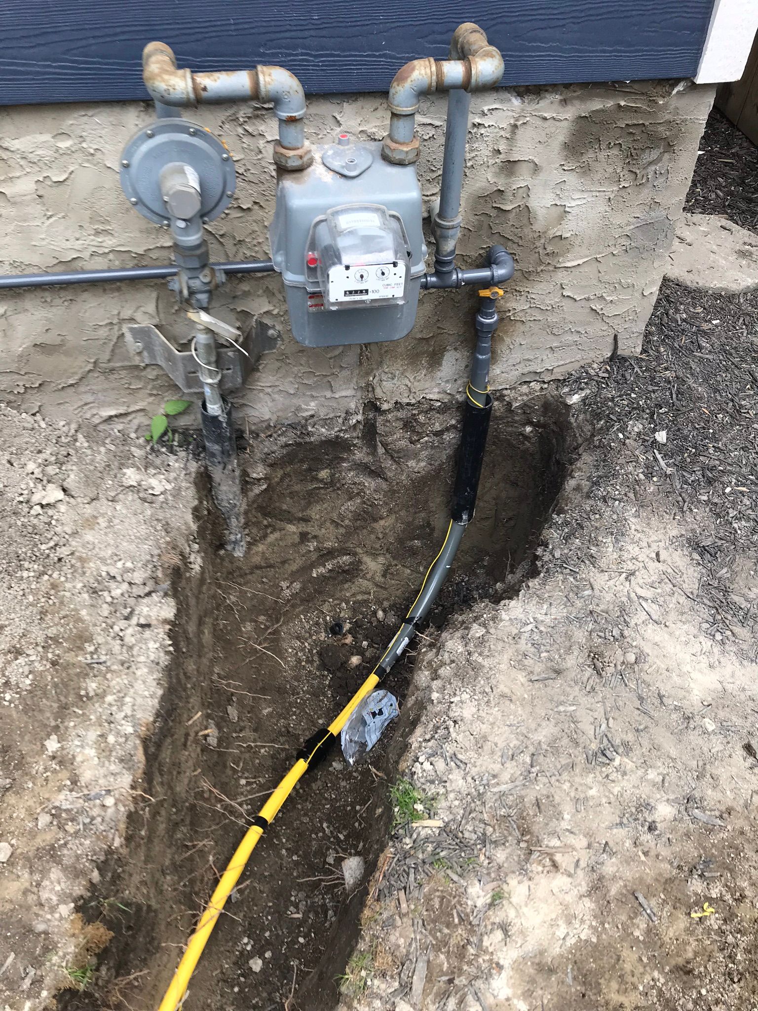 A gas meter is being installed in a hole in the ground.