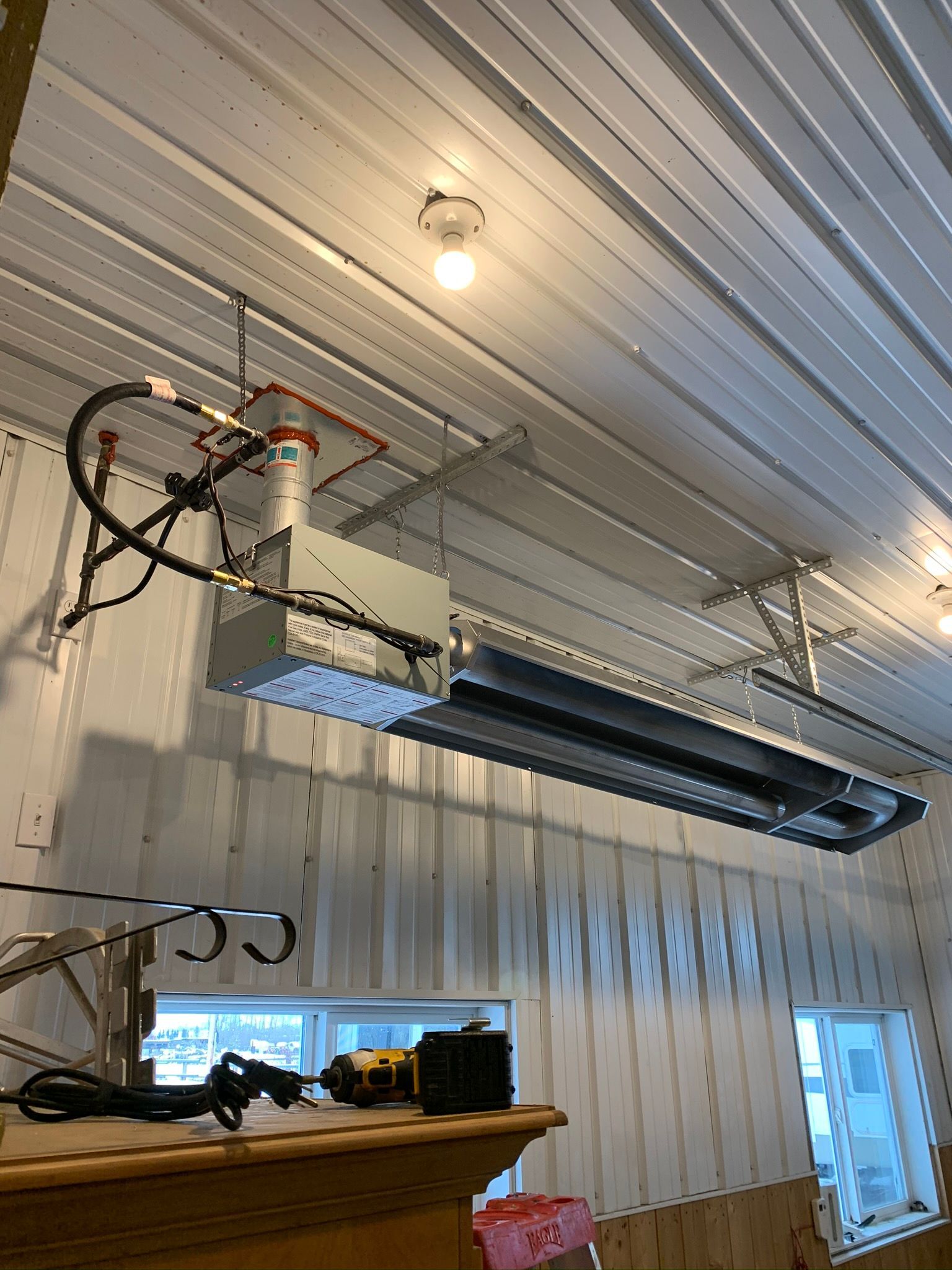 A large heater is hanging from the ceiling of a building.