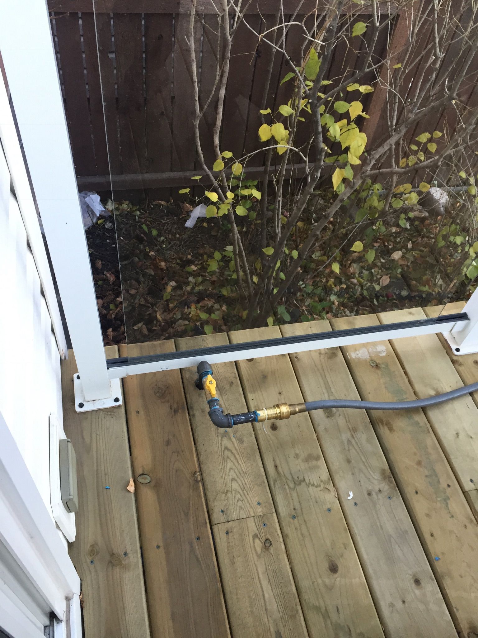 A hose is attached to a wooden deck next to a fence.
