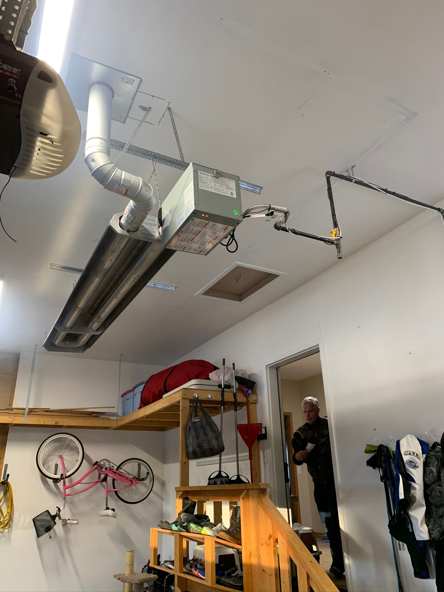 A man is standing in a garage with a ceiling fan hanging from it.