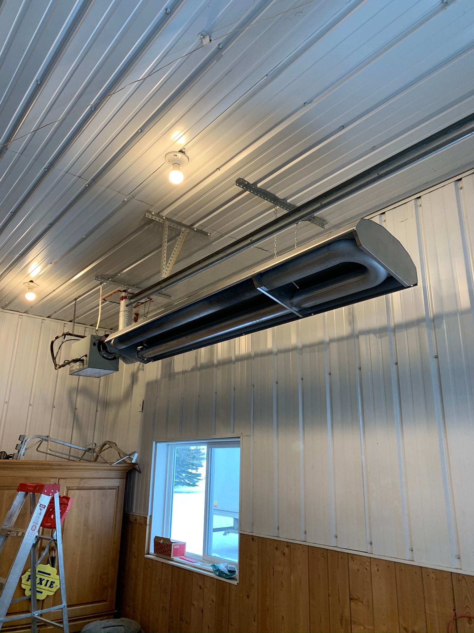 A large heater is hanging from the ceiling of a building.