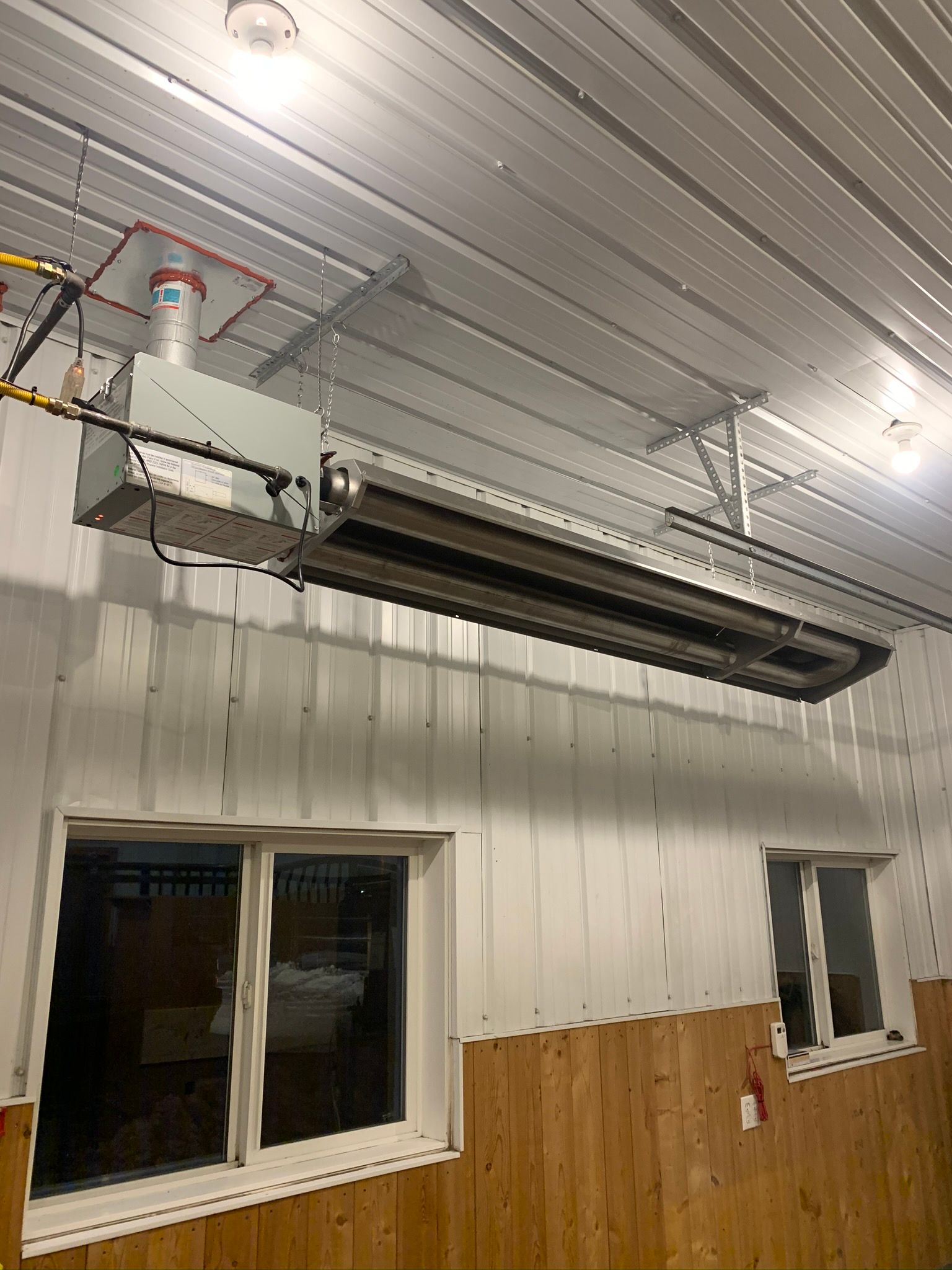 A large heater is hanging from the ceiling of a building.