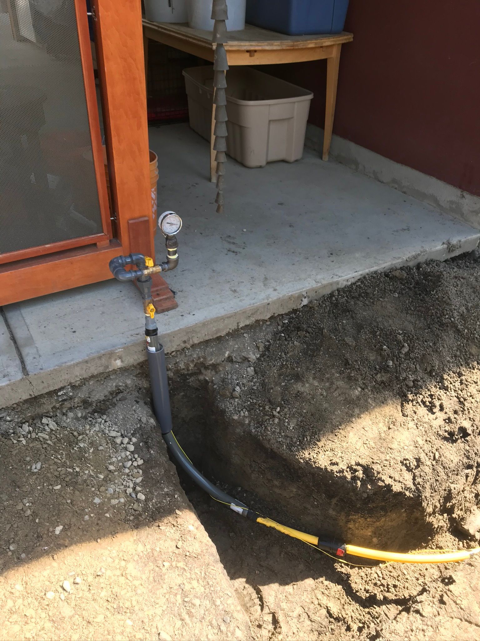 A hose is coming out of the ground next to a door.