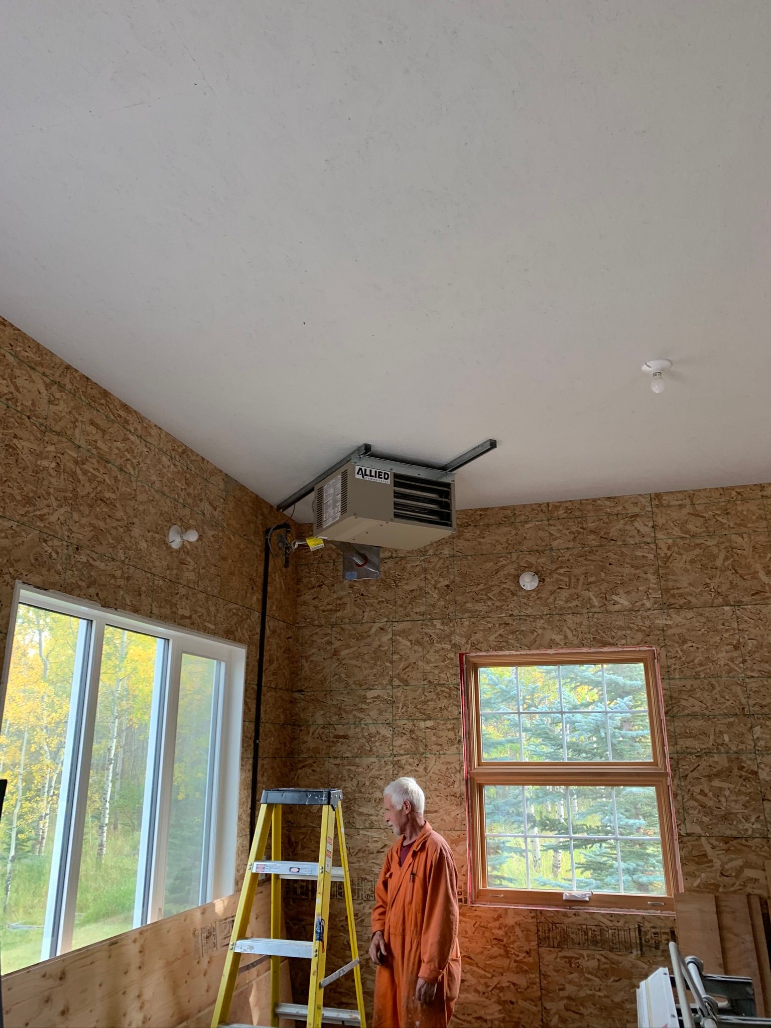 A man is standing next to a ladder in a room.