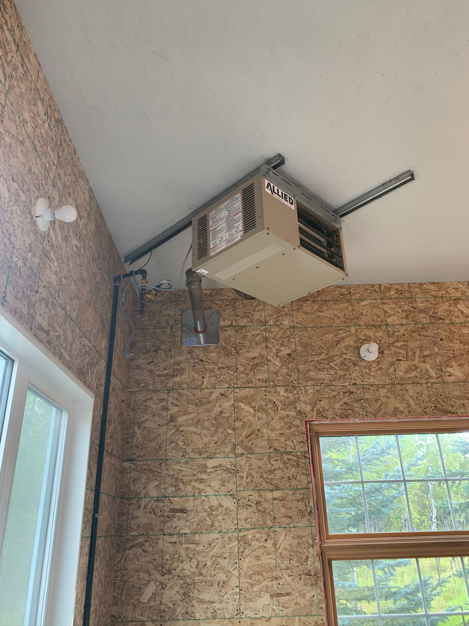 A projector is hanging from the ceiling of a room next to a window.