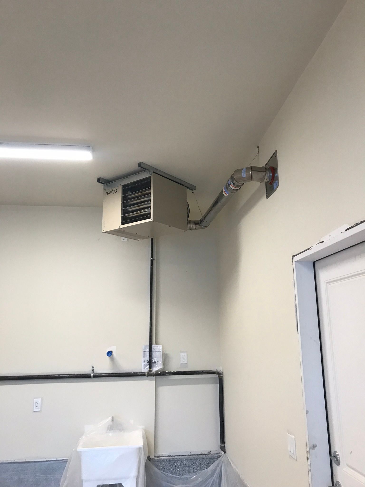 A laundry room with a washer and dryer and a heater hanging from the ceiling.