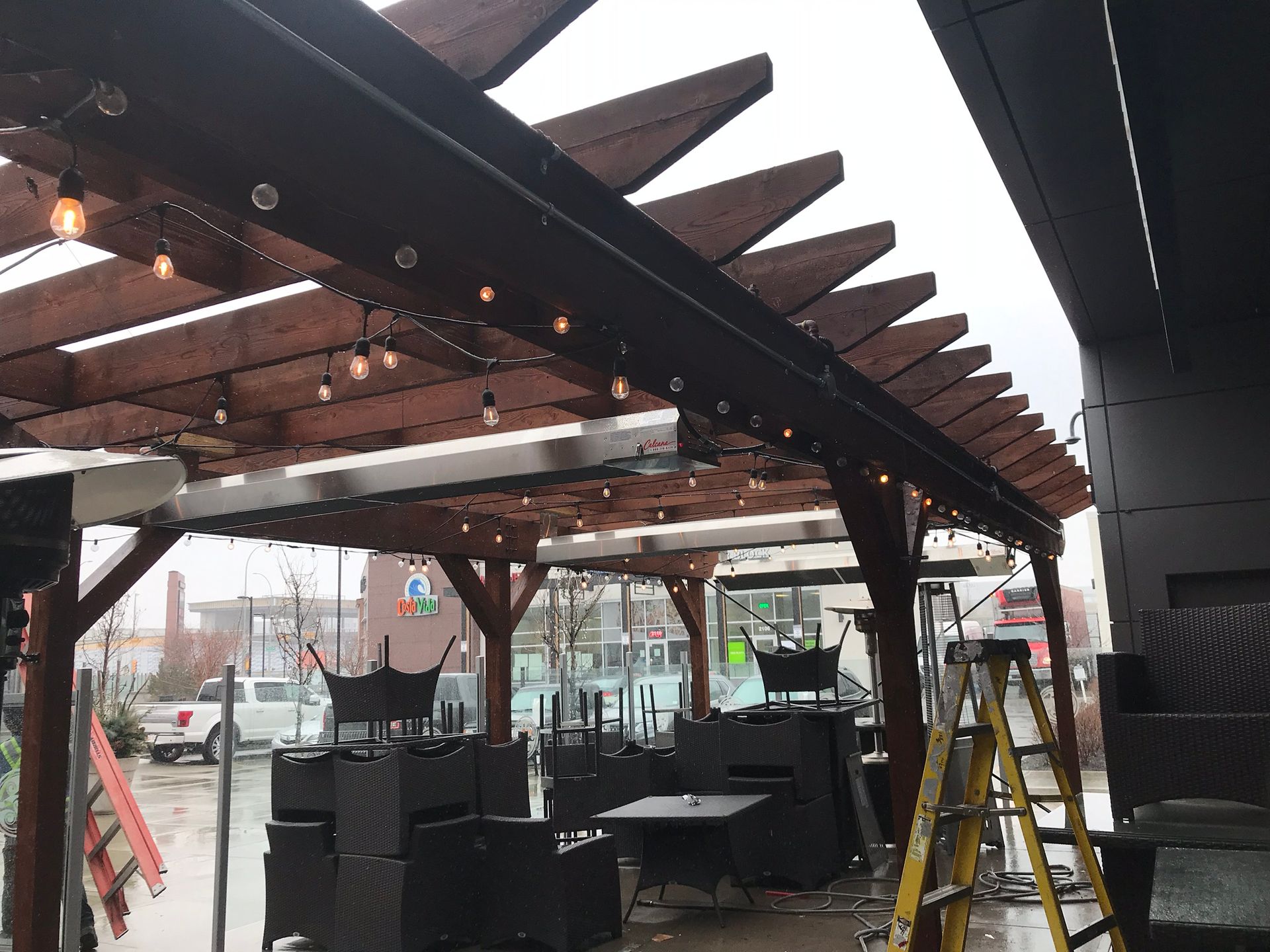 A restaurant with tables and chairs under a wooden pergola.