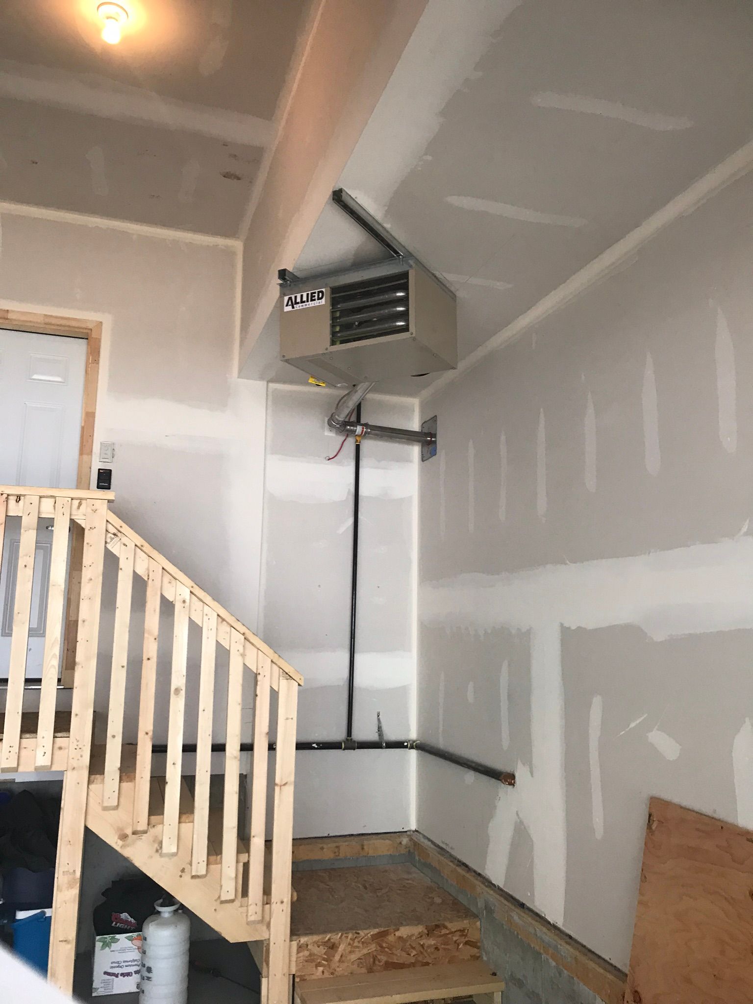 A garage with stairs and a heater on the ceiling.