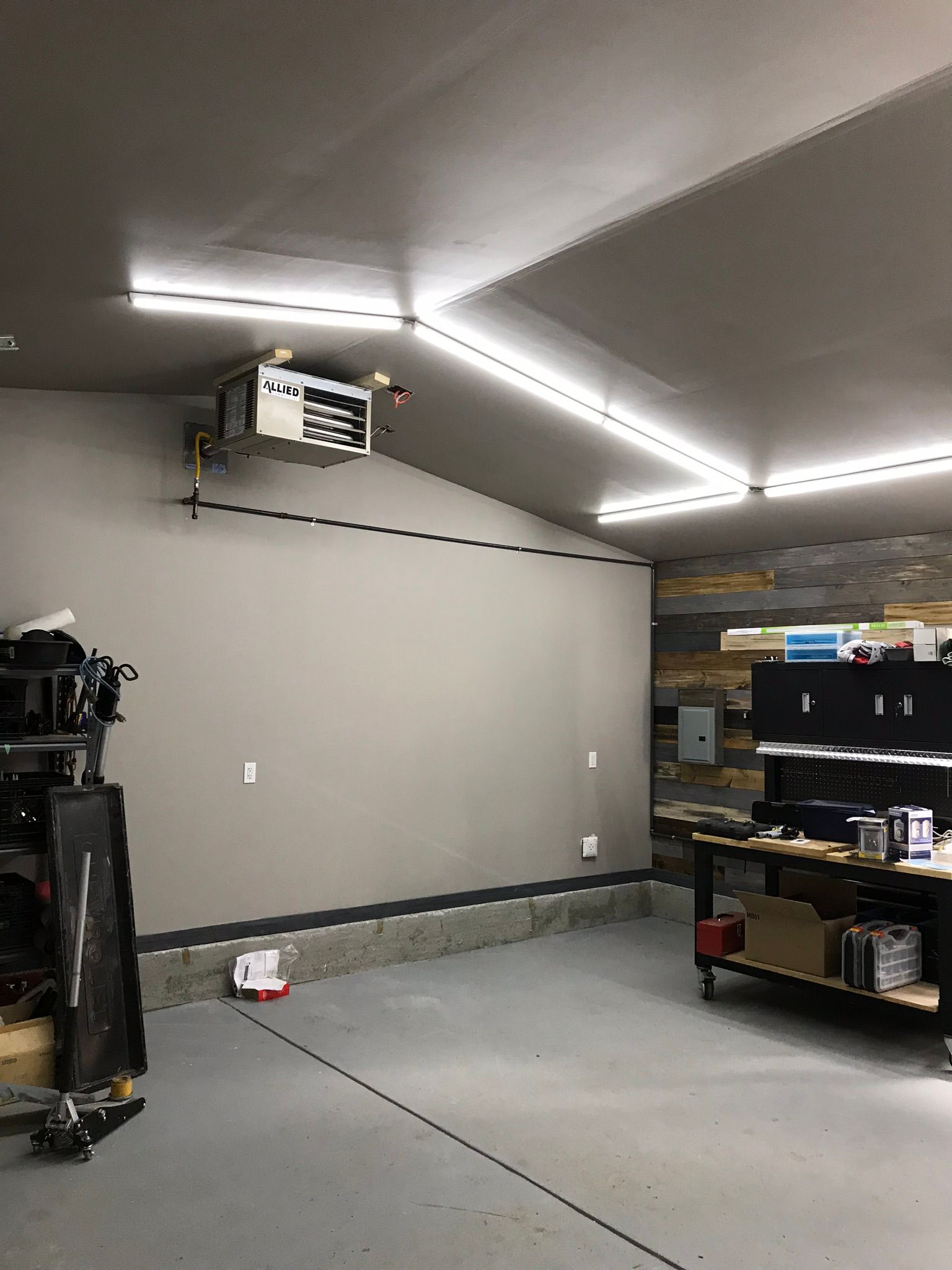 A garage with a workbench and a heater on the ceiling.