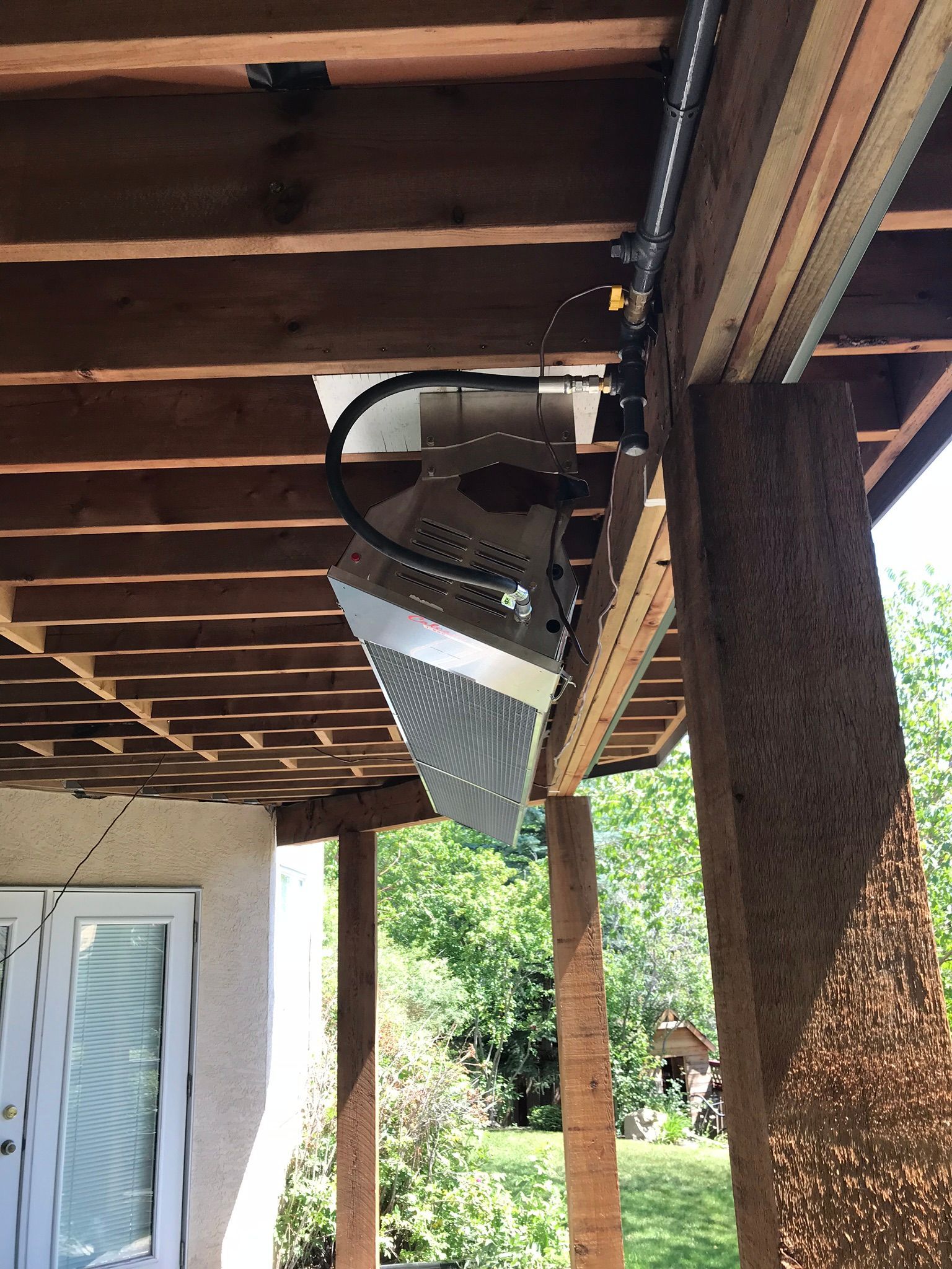 A heater is hanging from the ceiling of a wooden deck.