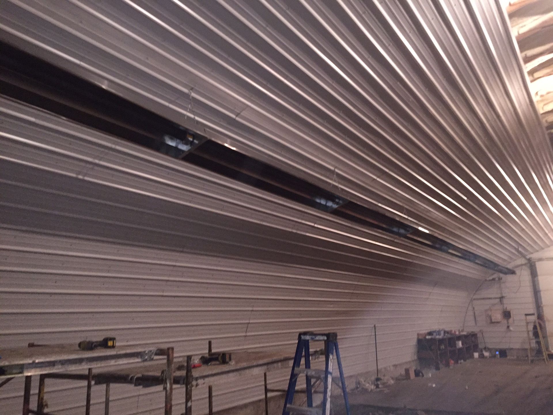 A ladder is sitting in a room with a metal ceiling.
