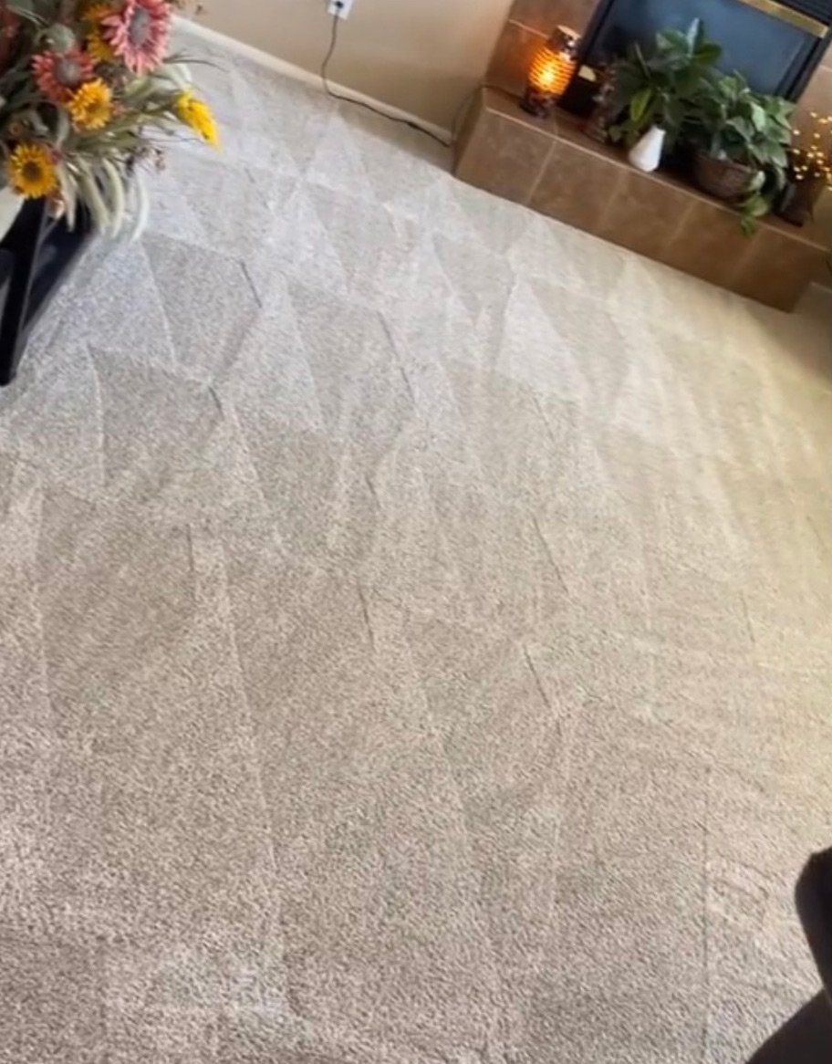 Carpet with geometric patterns, next to a fireplace and flowers.