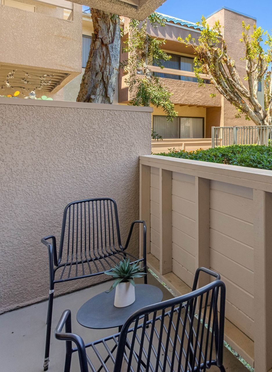 A balcony with two chairs and a table with a plant on it.