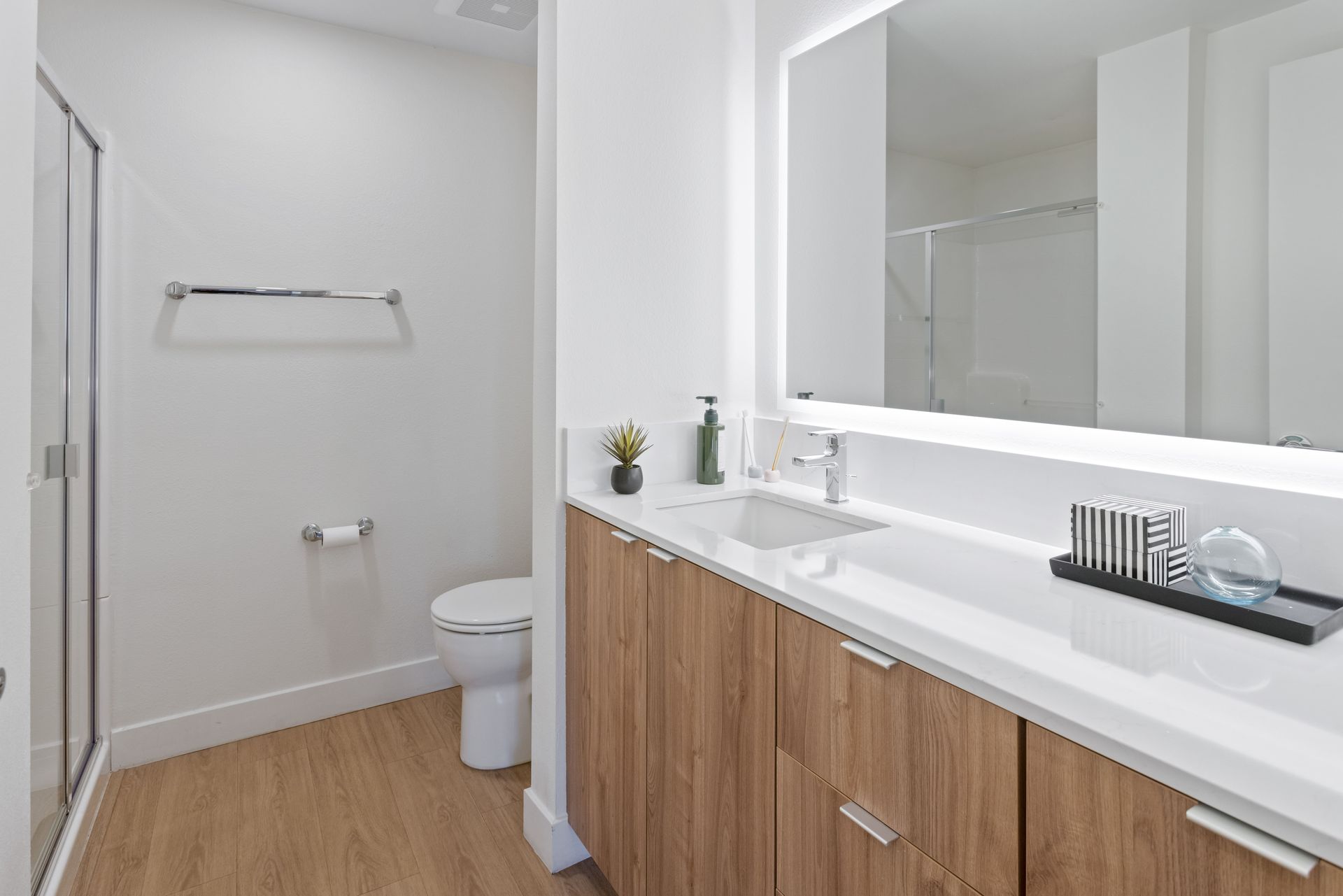 A bathroom with a toilet , sink , mirror and shower.