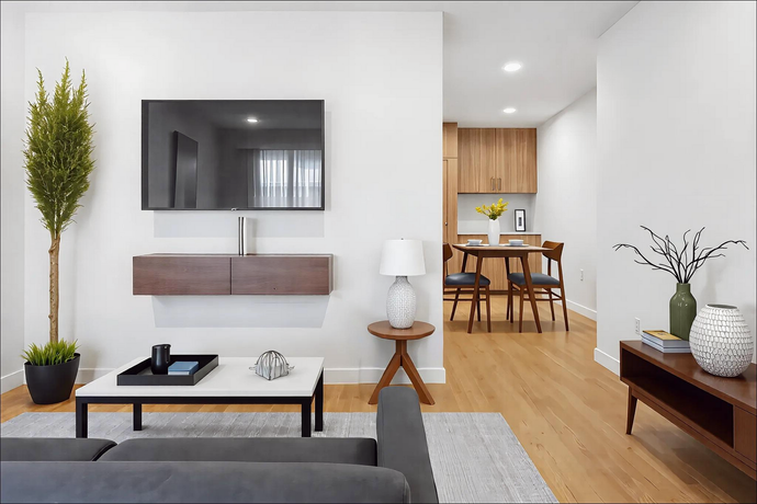 A living room with a couch and a flat screen tv on the wall.