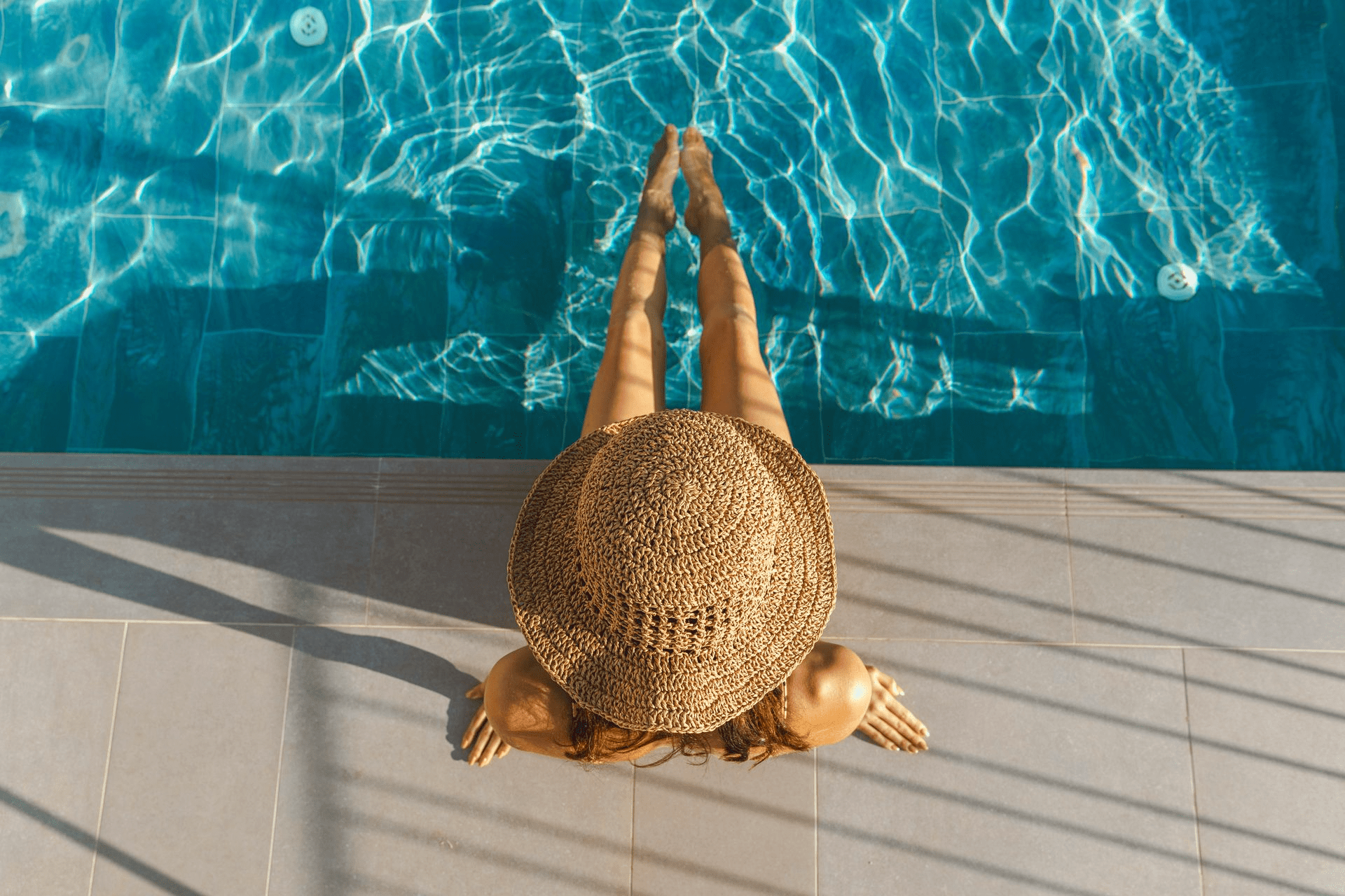 A woman is sitting on the edge of a swimming pool.