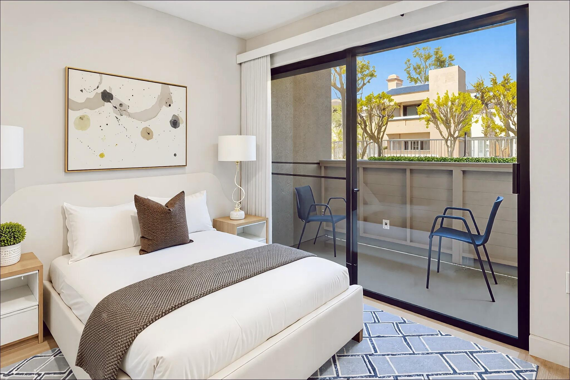 A bedroom with a large bed and a sliding glass door leading to a balcony.