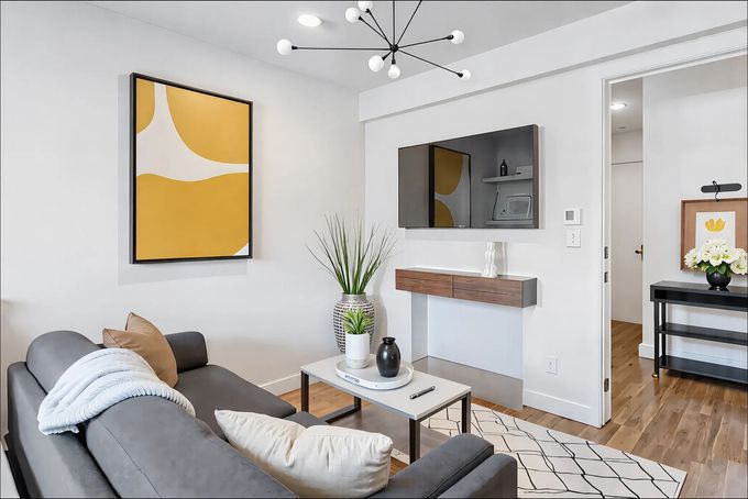 A living room with a couch and a flat screen tv on the wall.