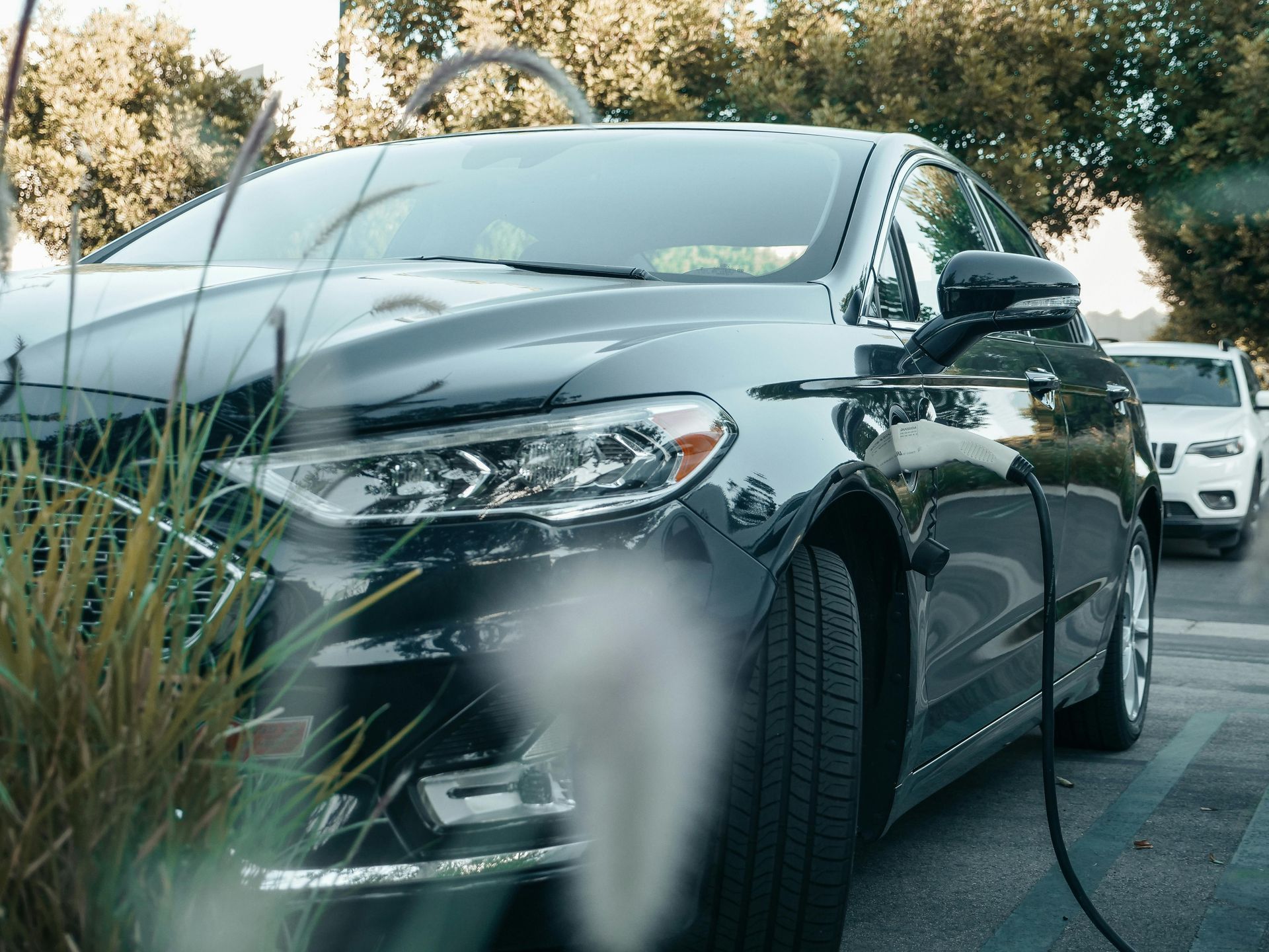 A black electric car is being charged at a charging station.