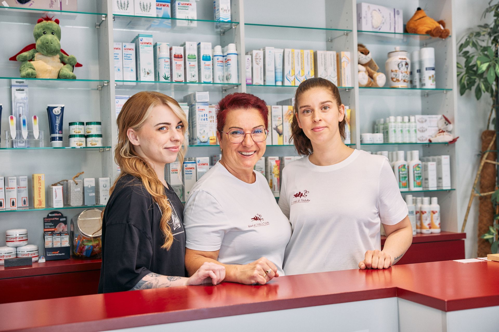 eine Gruppe von drei Frauen steht an einer Rezeption in einer Apotheke .
