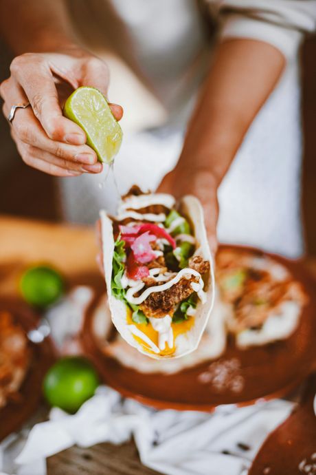 A person is squeezing a lime into a taco.